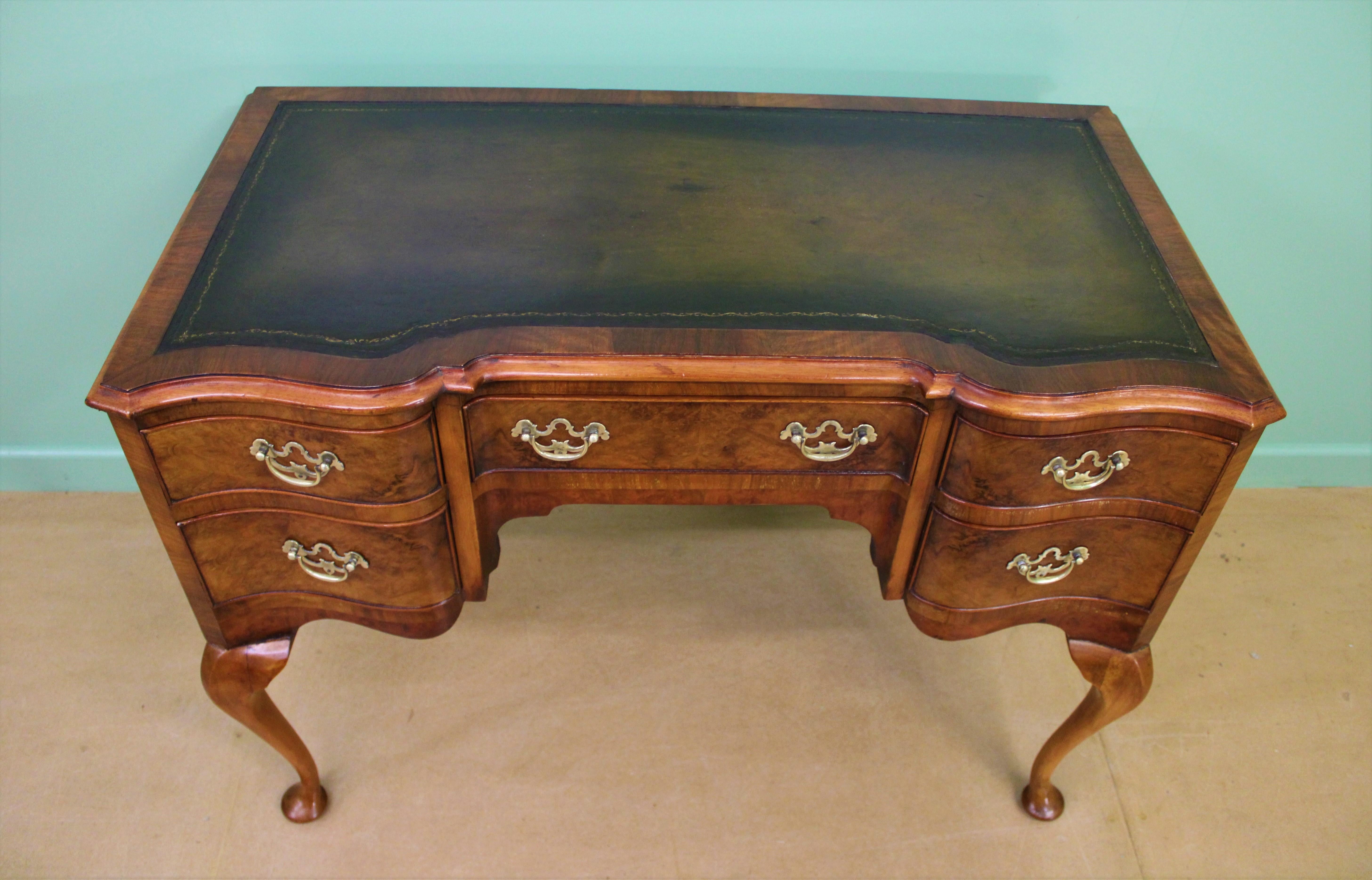 A very good Queen Anne style burr walnut serpentine fronted writing table, or desk. Well constructed in solid walnut with attractive burr walnut veneers. The top fitted with a sumptuous green leather writing surface. With a series of 5 drawers, all