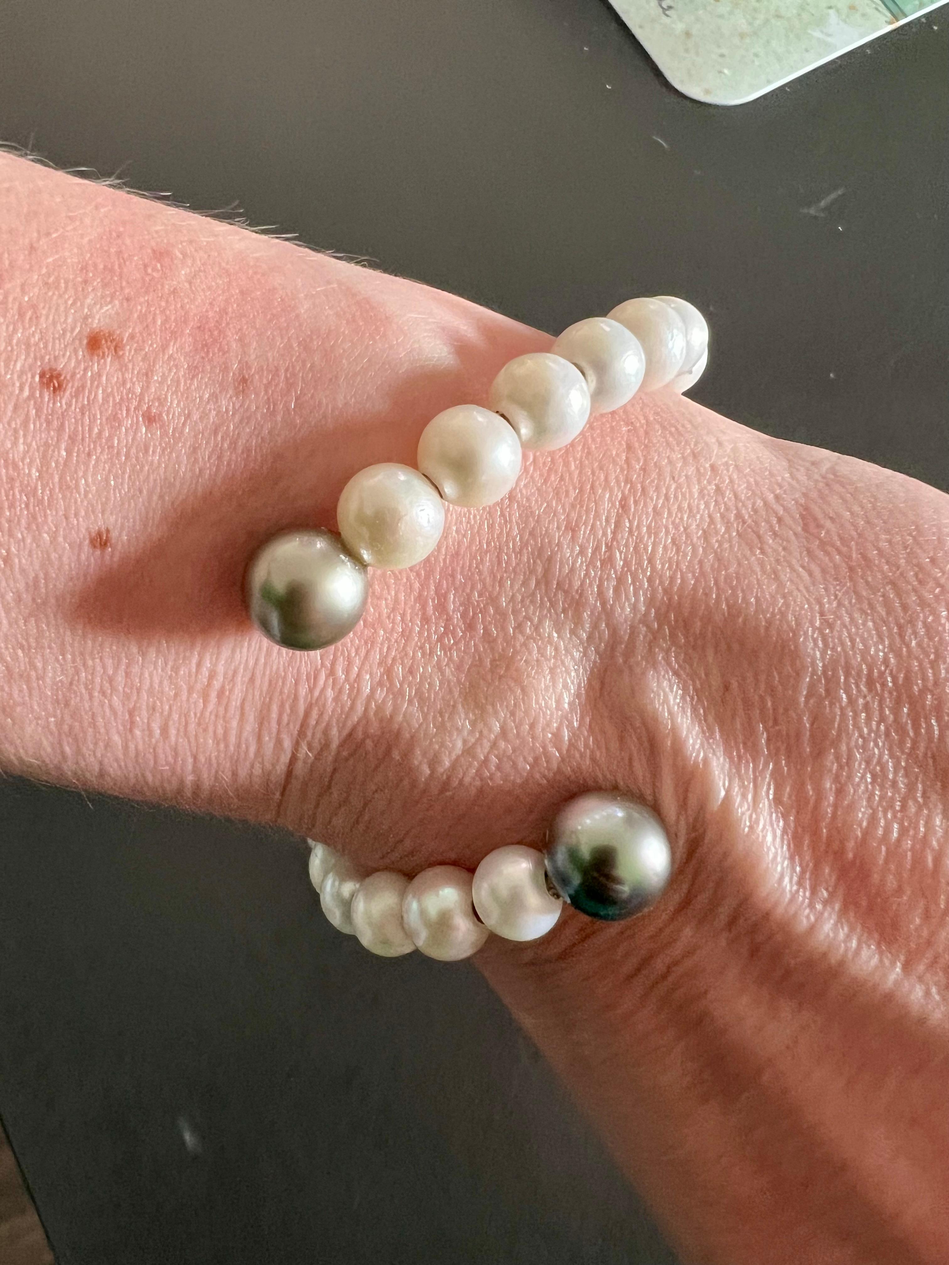 A graceful twist on timeless elegance — this serpentine-style bangle is crafted from creamy white freshwater pearls and finished with two stunning Tahitian pearls. Slightly bendable to fit S–L wrist sizes, it blends comfort with