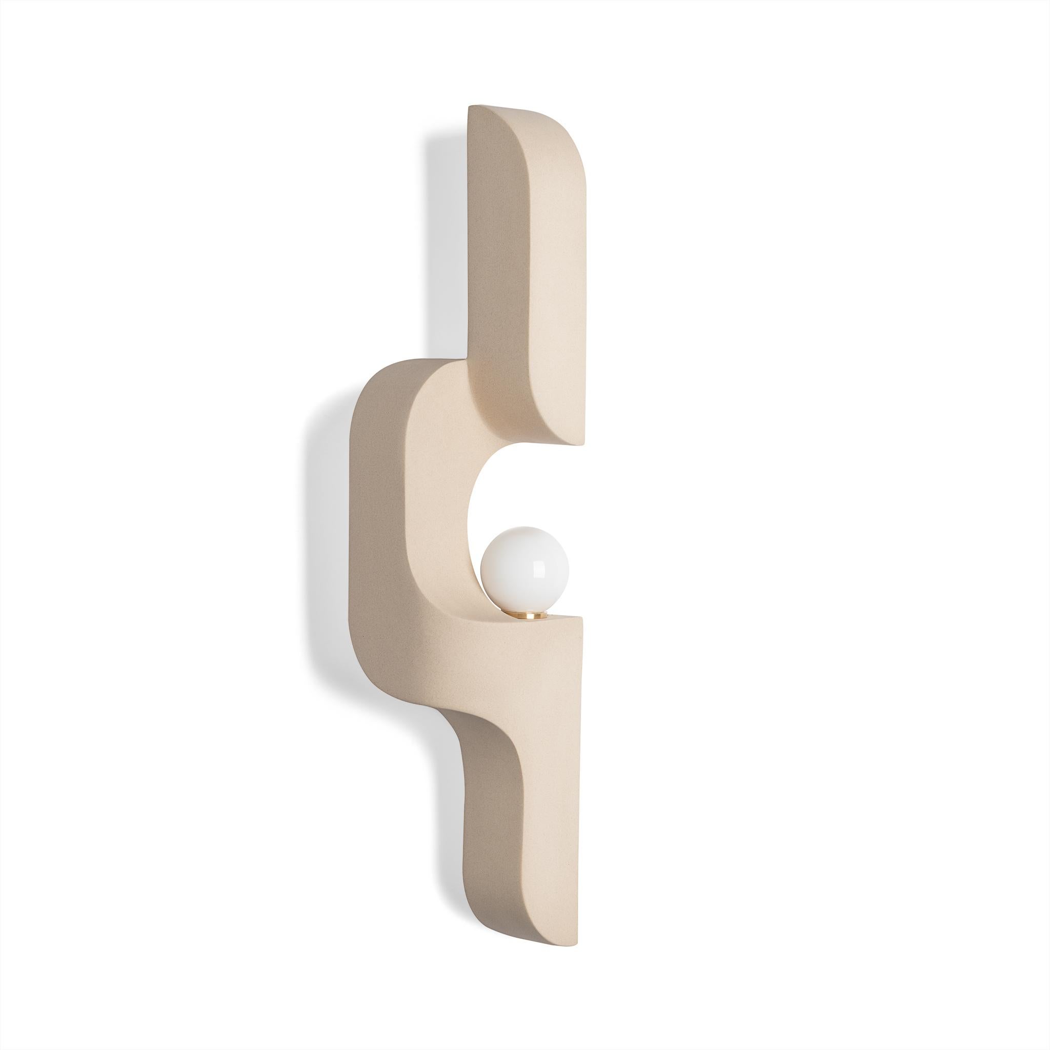 In this sandy slipcast ceramic wall sconce, generous curves are paired with crisp edges and the repetition of geometry to create a flow. The sconce snakes up and off the wall, a sculptural lighting piece that's understated, and almost artifact-like.
