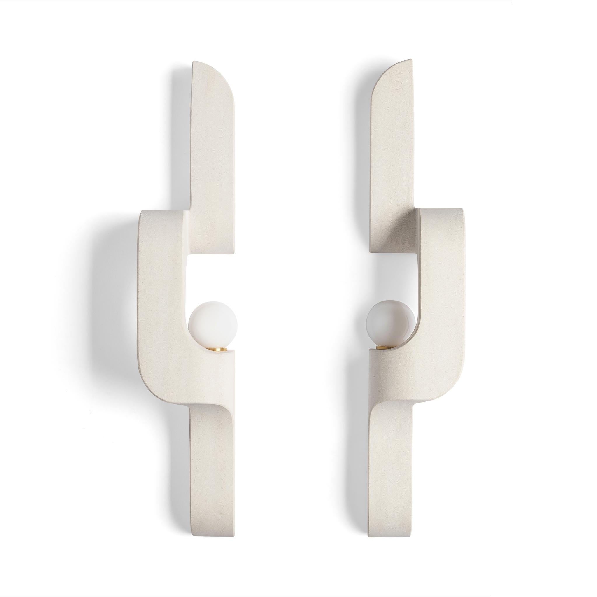 In this solid stone wall sconce, generous curves are paired with crisp edges and the repetition of geometry to create a flow. The sconce snakes up and off the wall, a sculptural lighting piece that's understated, and almost artifact-like.

This
