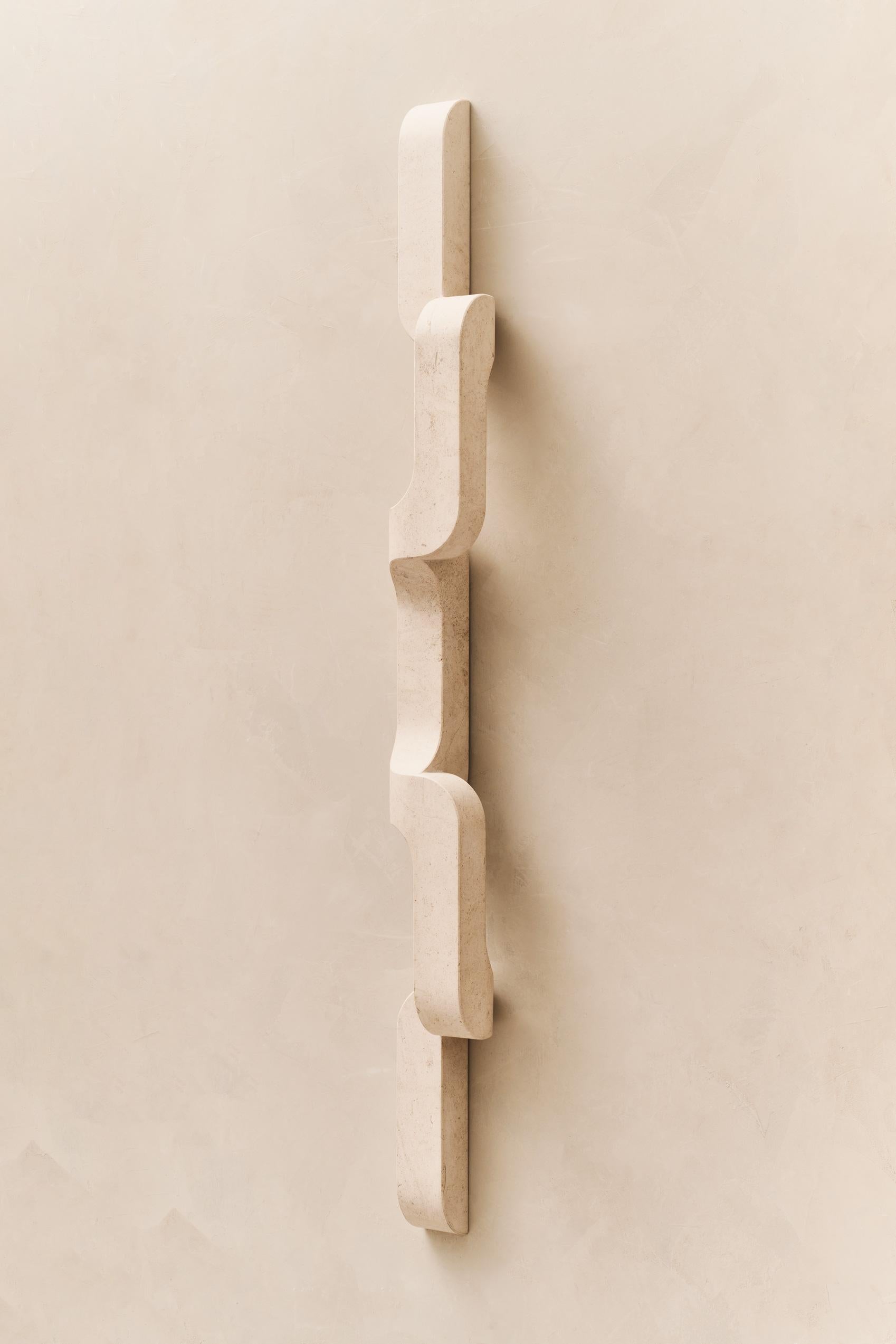 In this solid stone wall sconce, generous curves are paired with crisp edges and the repetition of geometry to create a flow. The sconce snakes up and off the wall, a sculptural lighting piece that's understated, and almost artifact-like. 

This