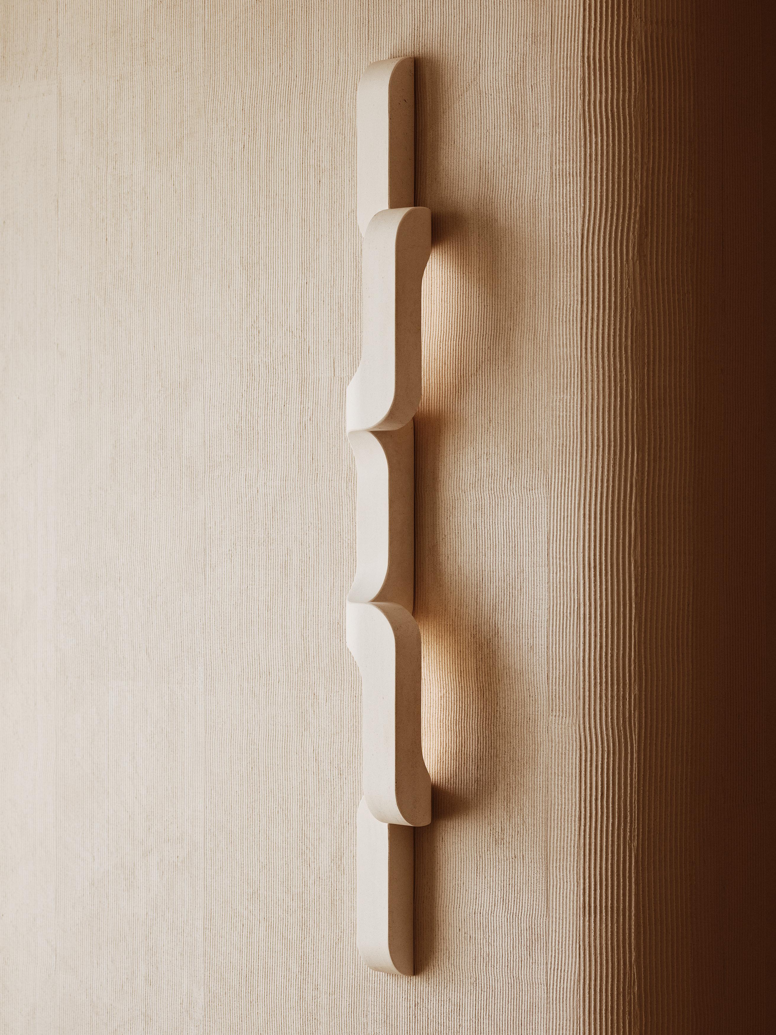 In questa applique in pietra massiccia, le curve generose sono abbinate a bordi netti e alla ripetizione della geometria per creare un flusso. L'applique si alza e si stacca dalla parete, un pezzo di illuminazione scultoreo e sobrio, quasi un