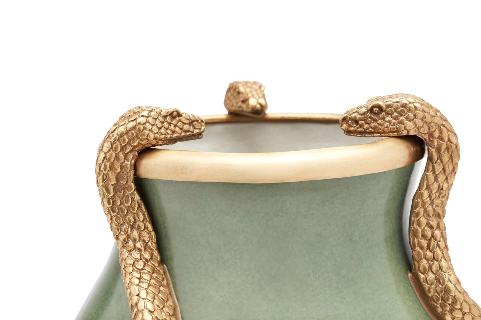 While most vases are made to showcase the flowers within, in the case of SERPENTIS it's what's on the outside that counts. Painted in dusty green with brass accents, this intriguing ceramic design is detailed with three gilded serpents, slithering