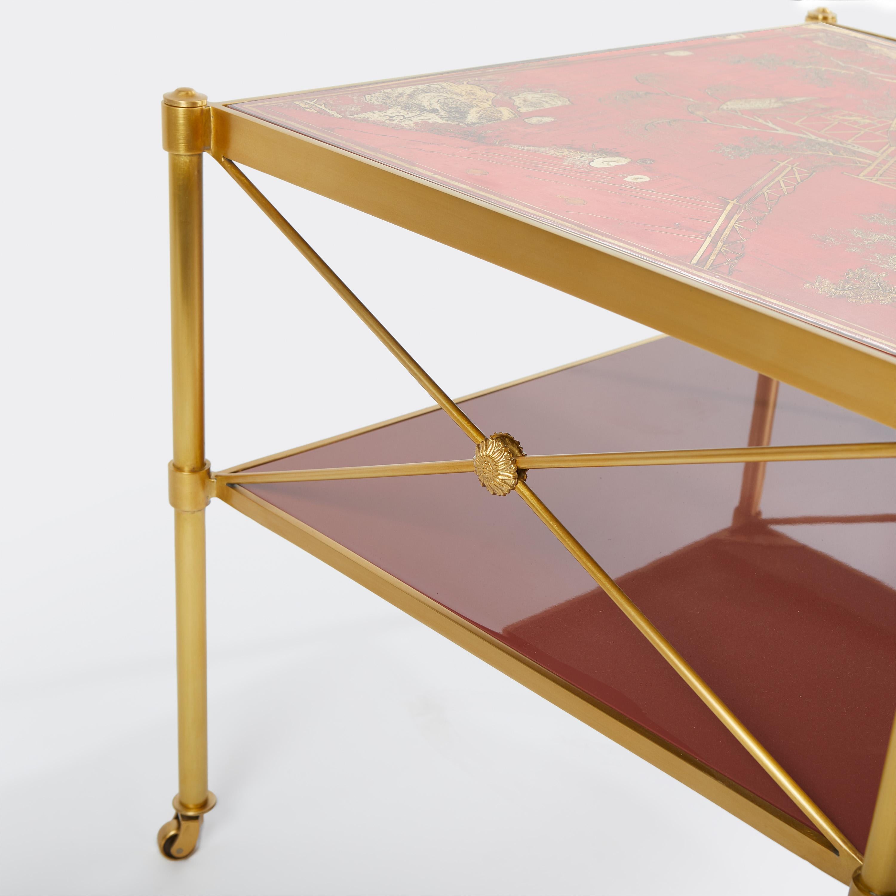 The Sert side tables in red, designed by David Duncan. Each table top features a hand painted, one of a kind Chinoiserie panel. With giltwood framed lacquered panel inset top with glass cover, and a lacquered red wood panel second tier. Each table