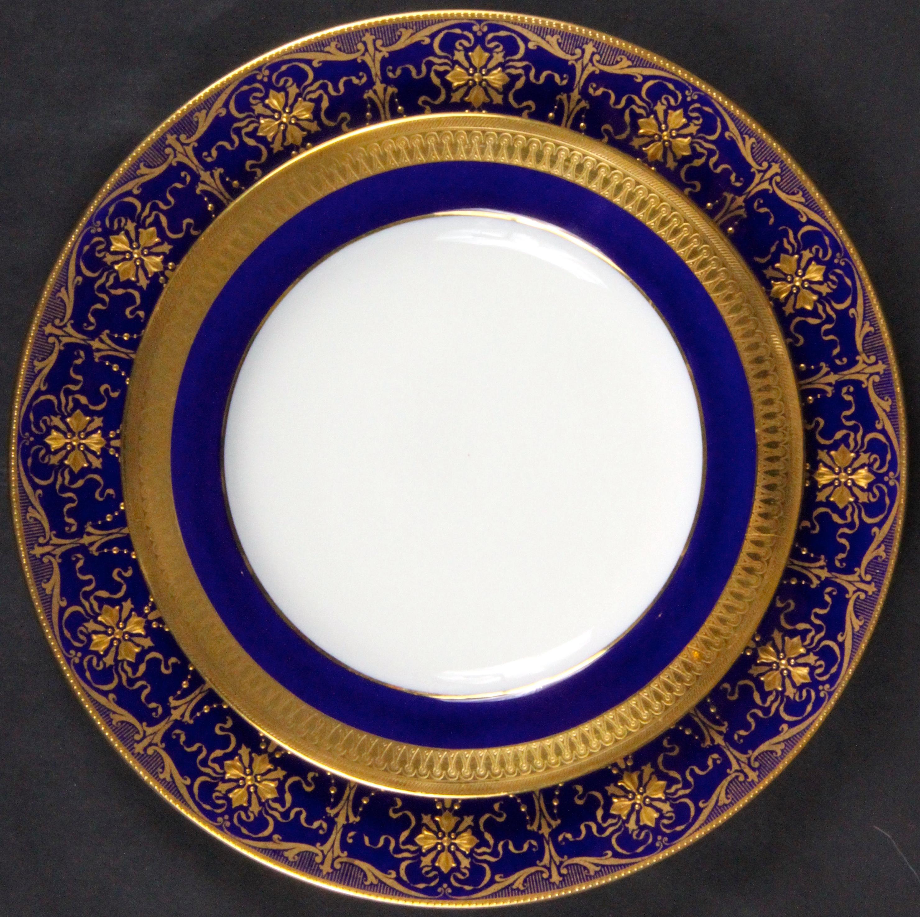 These 12 Minton, stoke-on-trent, England 22-karat gold encrusted service or dinner plates feature a cobalt border divided by columns of lotus flowers, between the columns lie stylized flowers enhanced with ribbons and gold beading, all rendered in