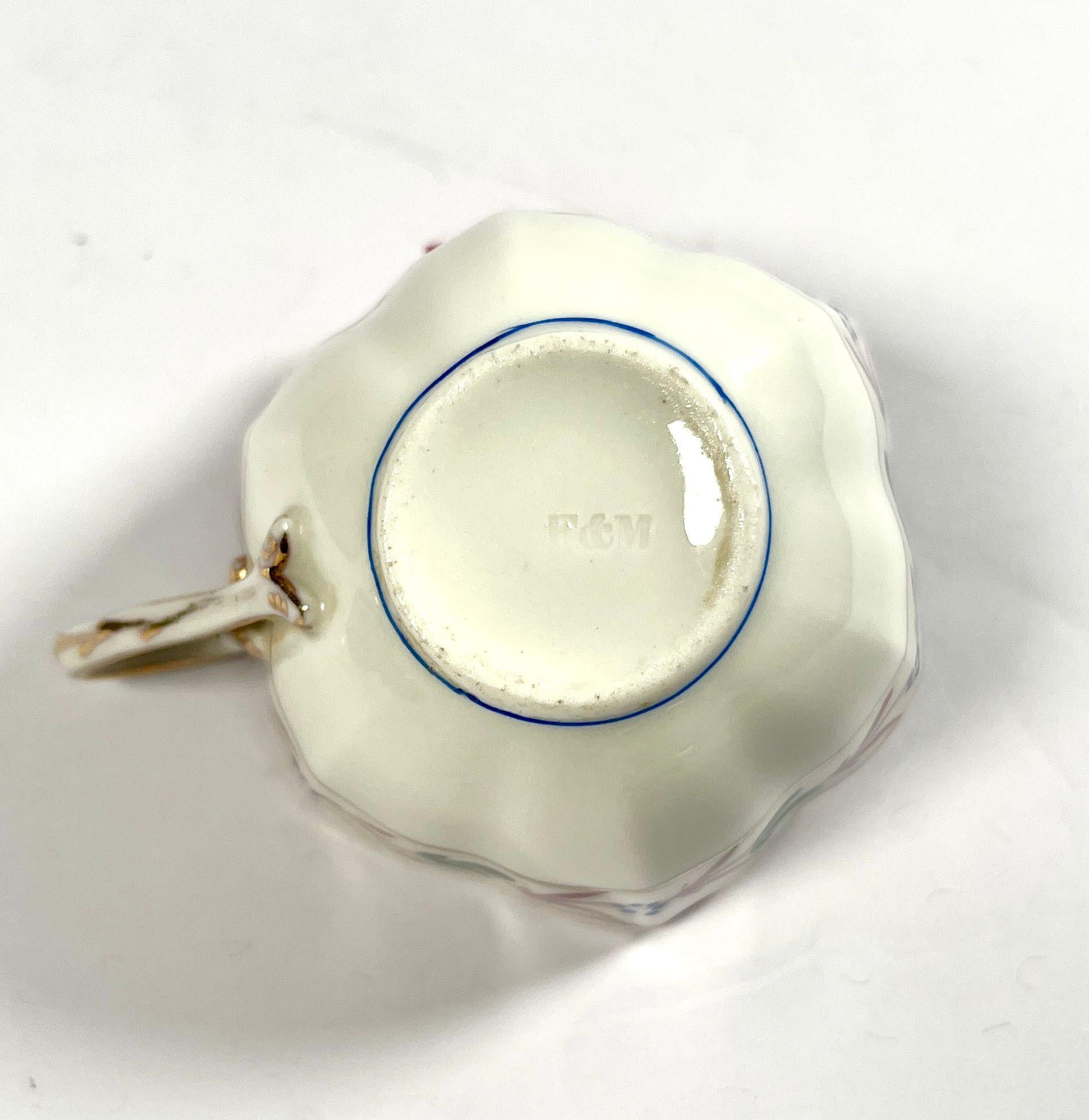 Set di 5 tazze e piattini in porcellana della manifattura Fischer e Mieg.
Le tazze, a forma di fiore aperto, presentano una ricca decorazione floreale multicolore e dorata. Il bordo è evidenziato da una linea dorata e la fascia superiore mostra un