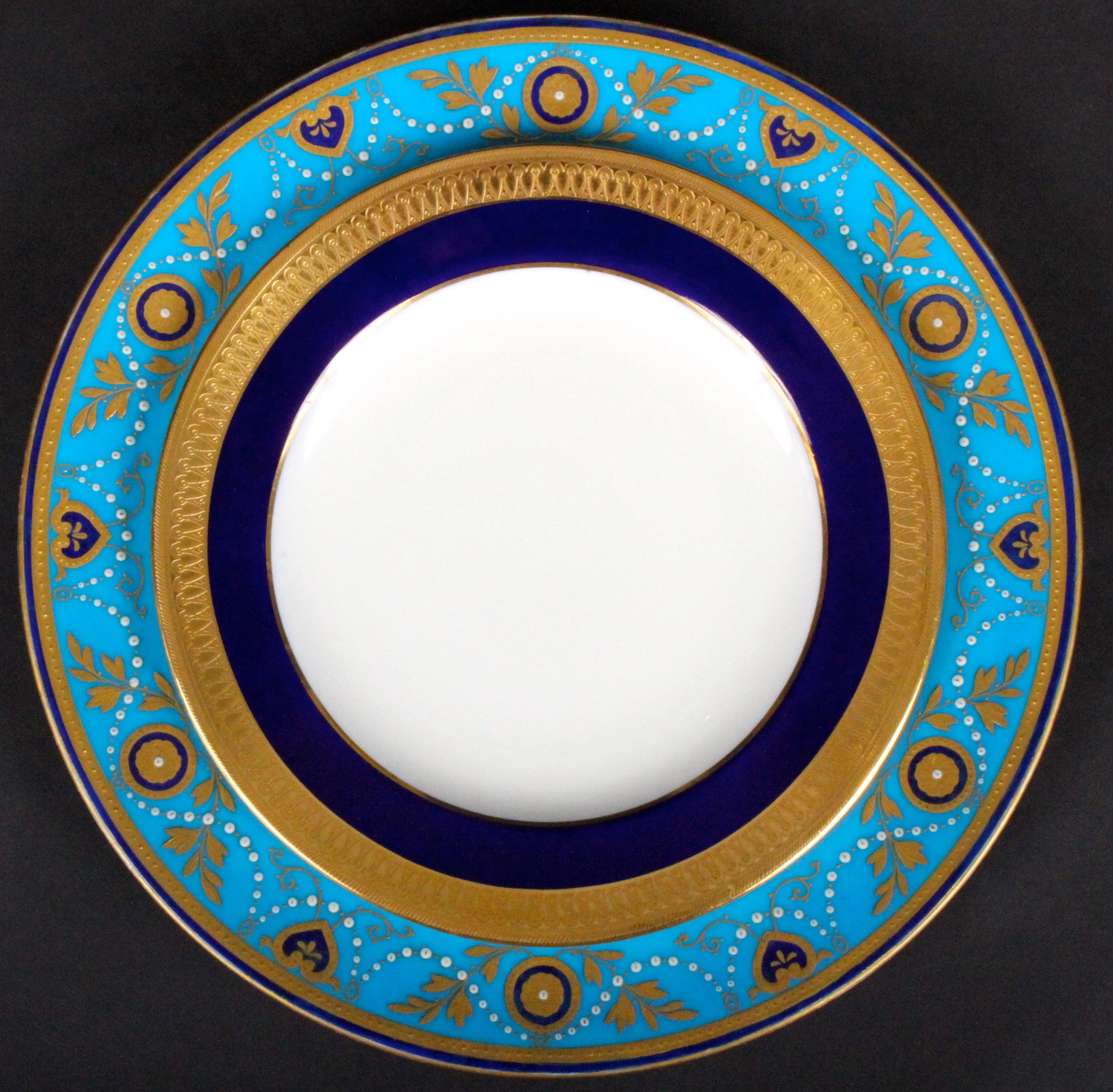 This is a set of 12 armorial-ware 22-karat gold encrusted and raised-paste gold porcelain dinner or service plates, with 12 coordinating plates. They were made by Minton, Stoke-on-Trent, England. The plates feature Minton’s most popular color,