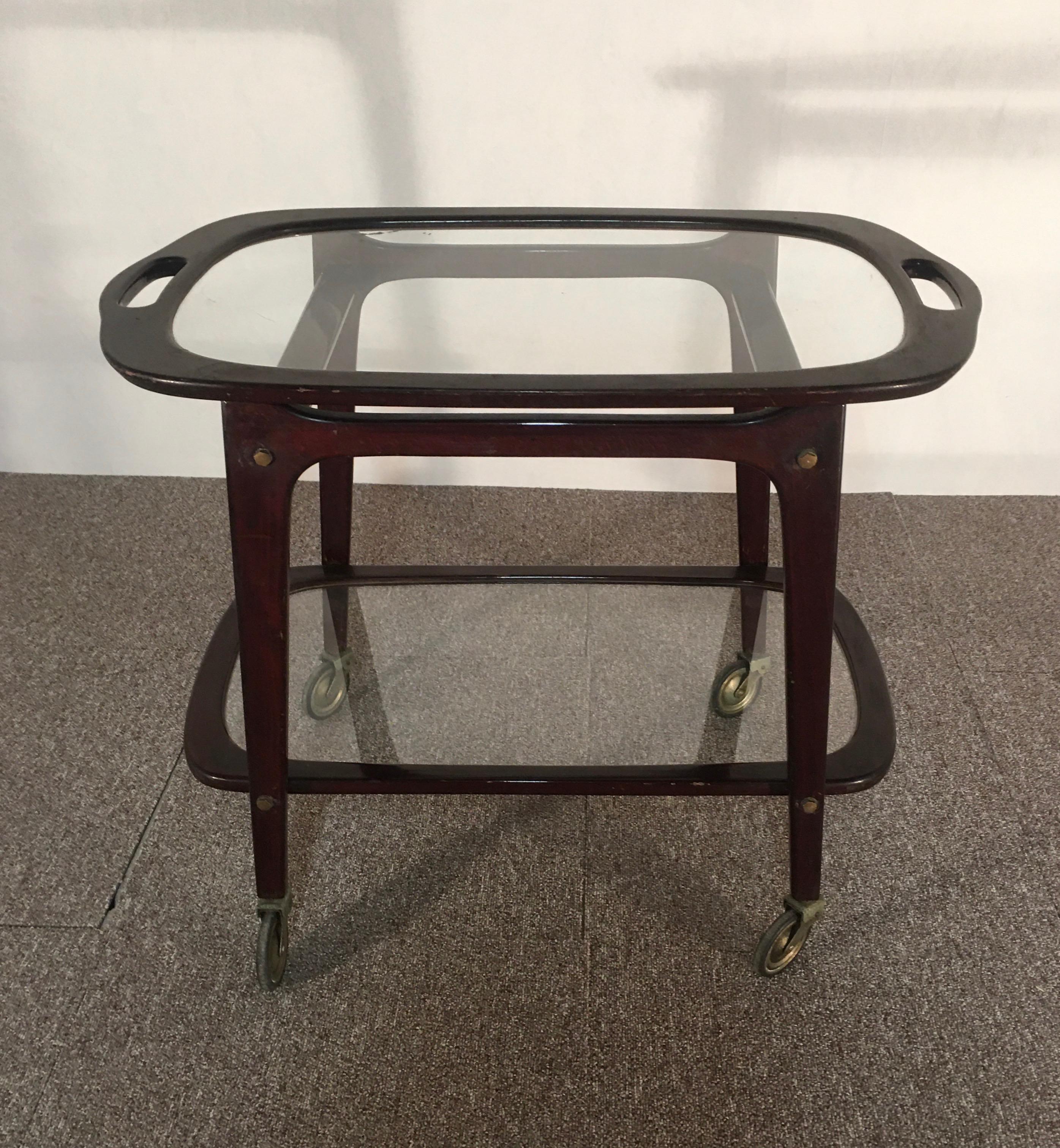 The cart is in mahogany stained beech. IT has a double glass top. With casters. Good condition.
