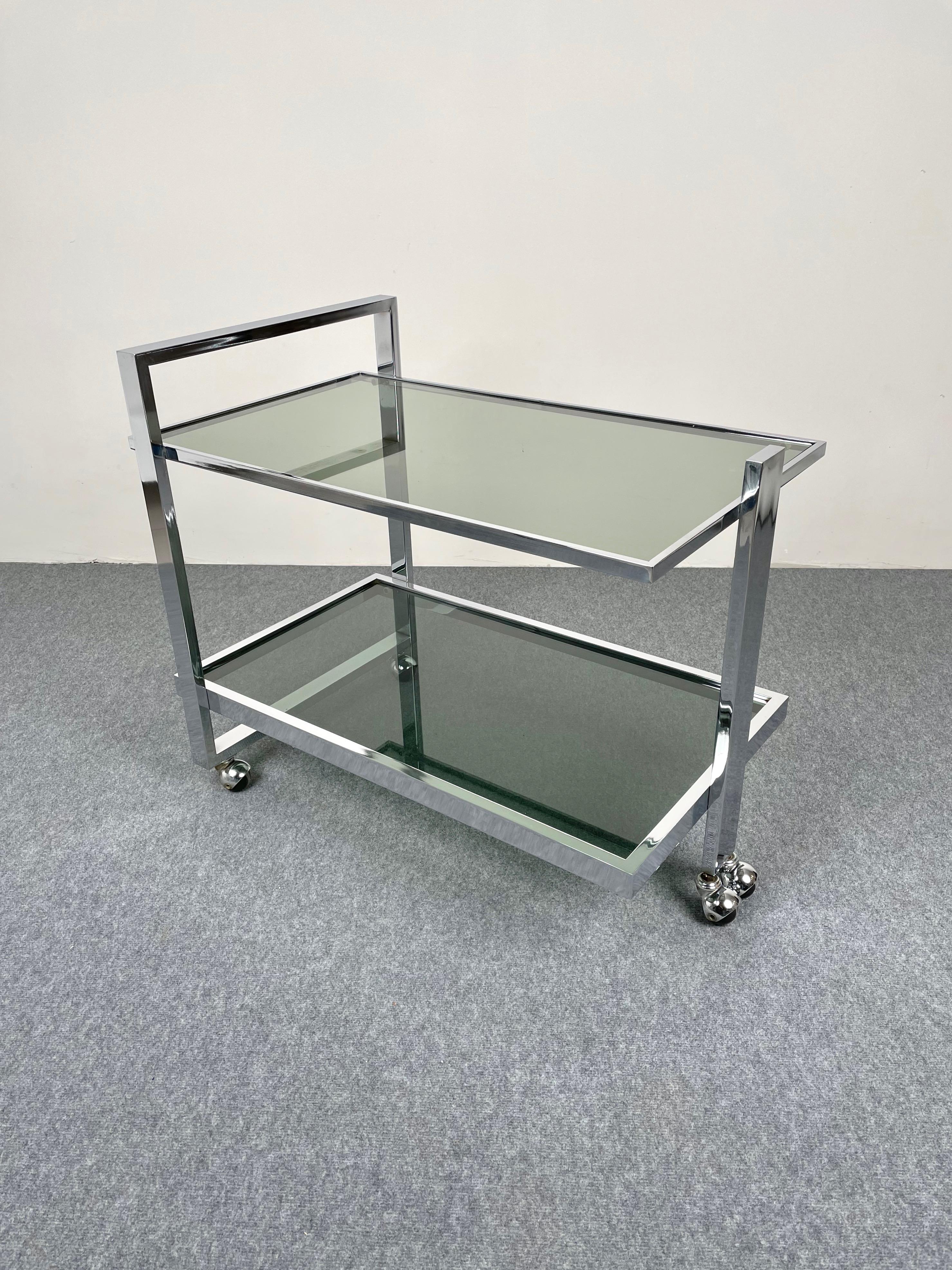 Serving bar cart serving trolley in the style of the Italian designer Romeo Rega in a chrome structure and two smoked glass shelves. Made in Italy, circa 1970.
