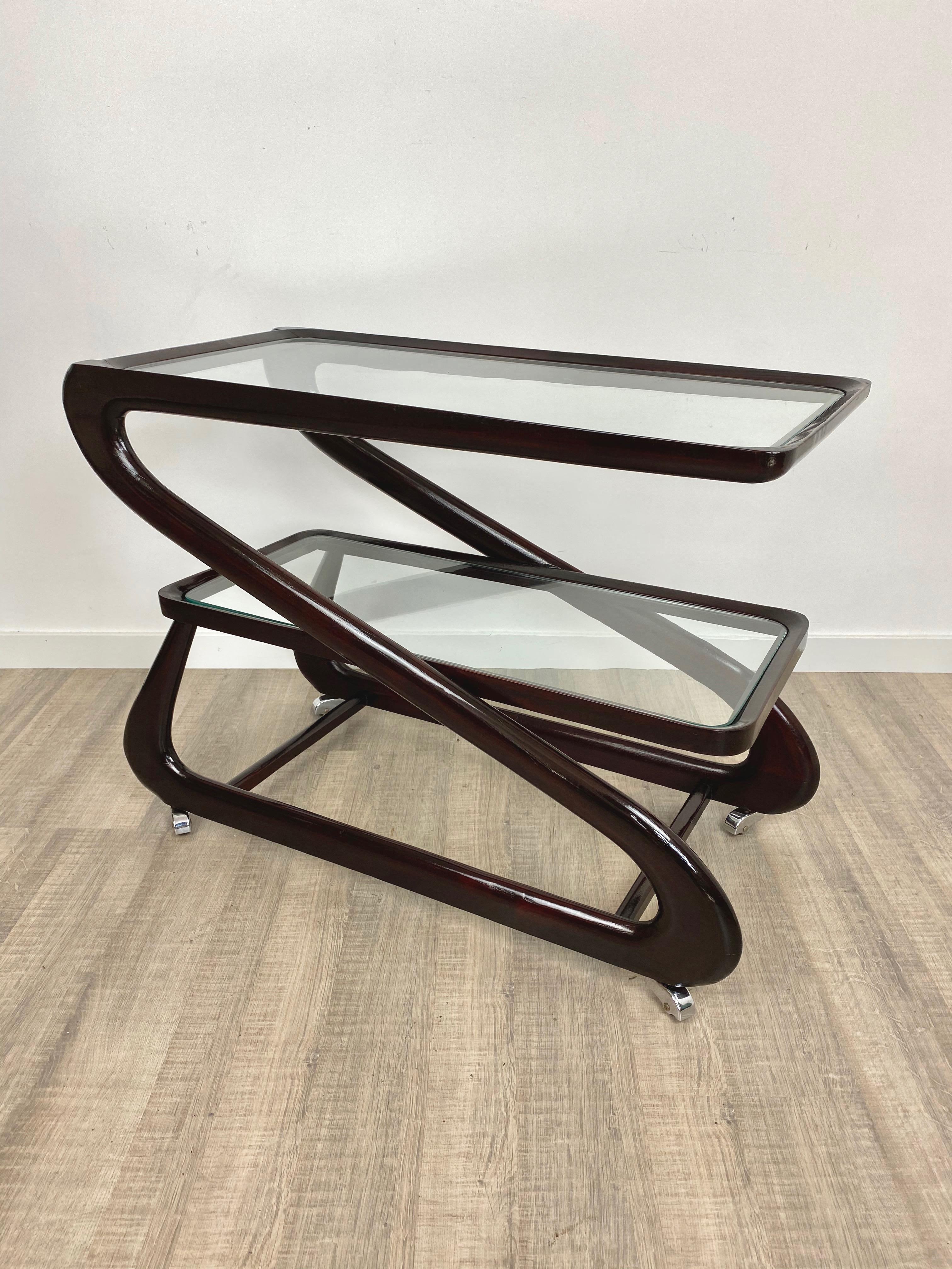 Serving bar cart featuring two glass shelves, in a mahogany wood dynamic structure, by the Italian designer Cesare Lacca. Made in Italy, circa 1950.