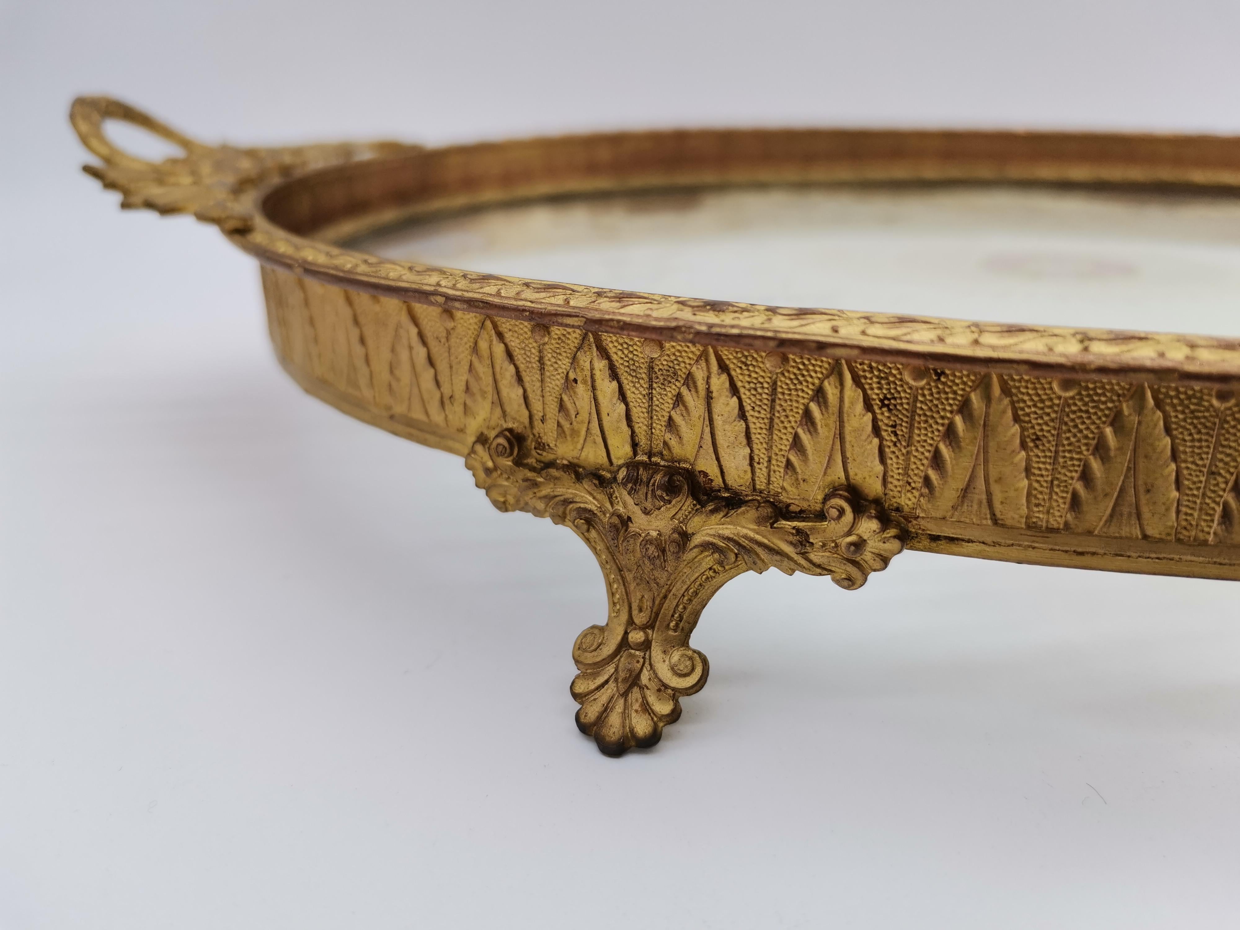 A serving tray made of brass and glass with a embroidery.