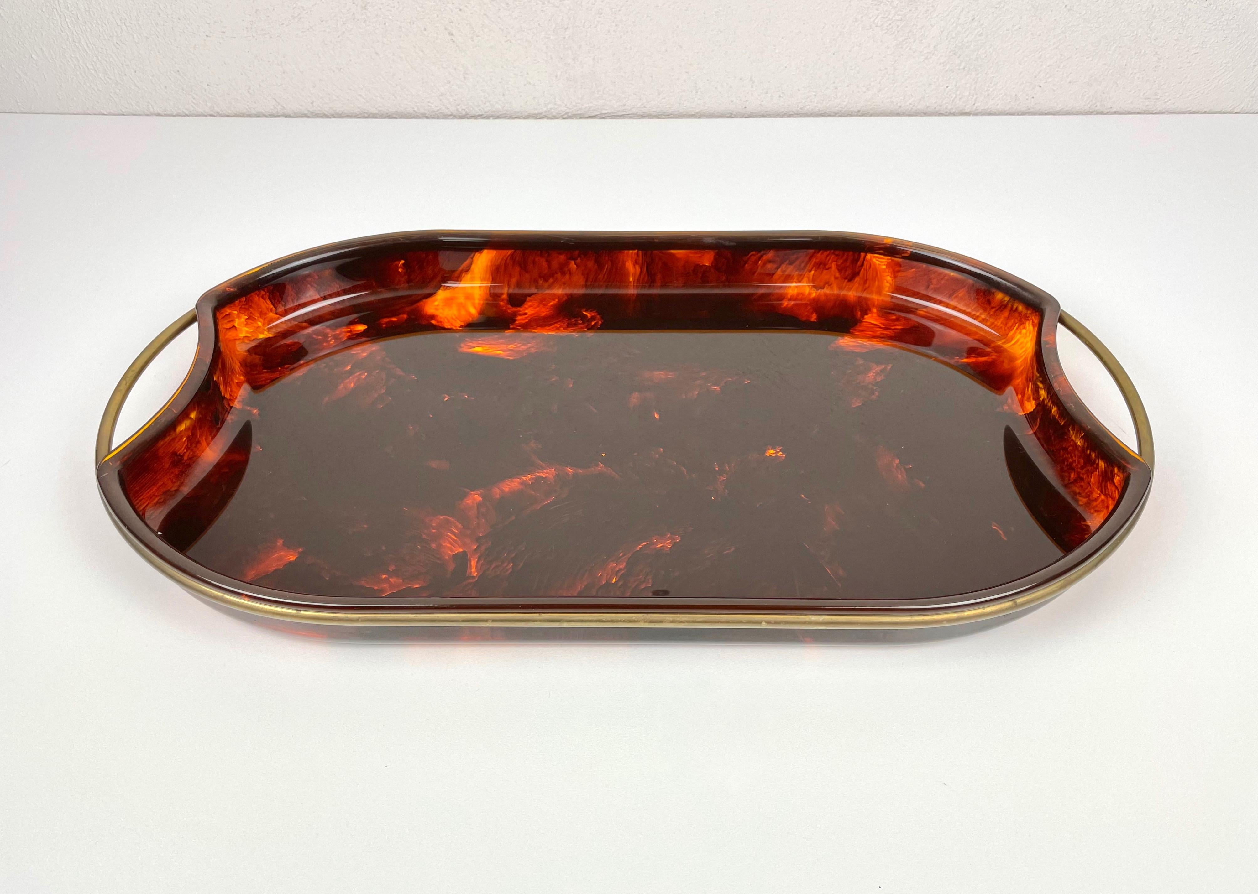 Oval serving tray in faux tortoiseshell-effect Lucite featuring brass handles and borders.

 Made in Italy in the 1970s.