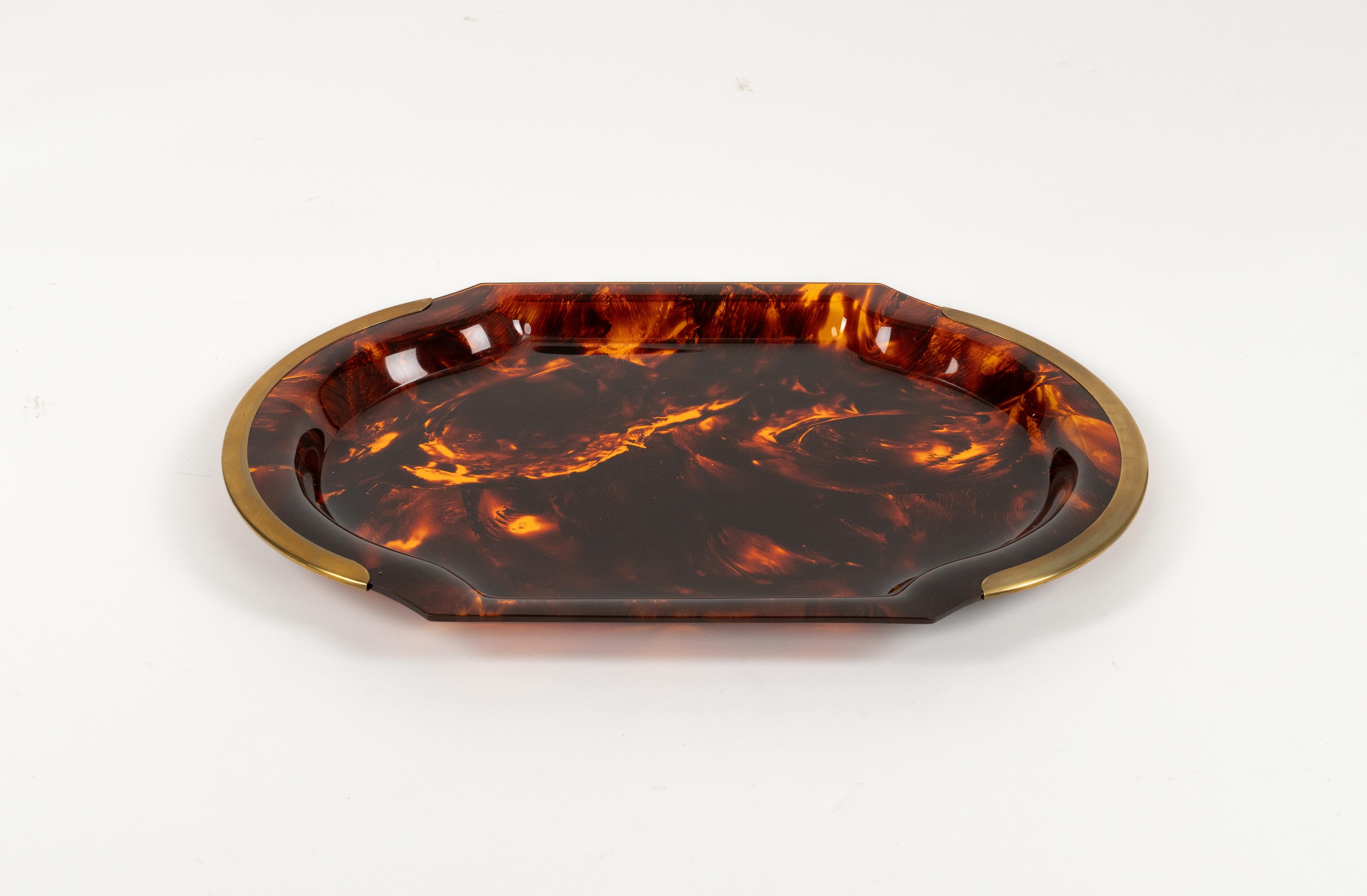 Midcentury amazing oval serving tray in faux tortoiseshell-effect Lucite featuring brass handles attributed to Team Guzzini.

Made in Italy in the 1970s.   

It's an iconic tray or plate made of lucite that will wow your guests and is perfect for a