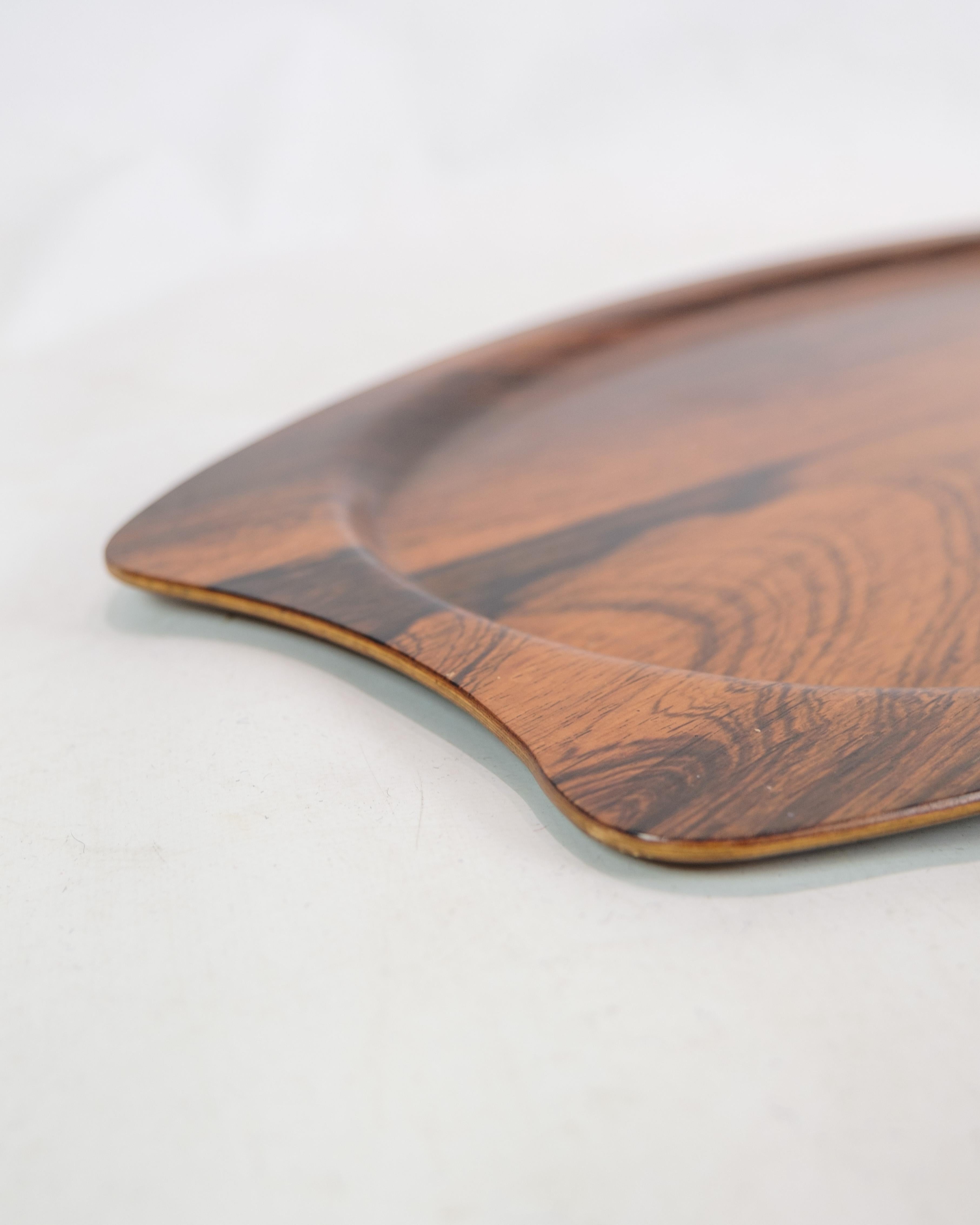 This serving tray is a beautiful example of Danish design from the 1960s, made of rosewood and produced by Silva. Bakken exudes a timeless elegance and craftsmanship characteristic of this era of furniture design.

The warm tone and beautiful grain