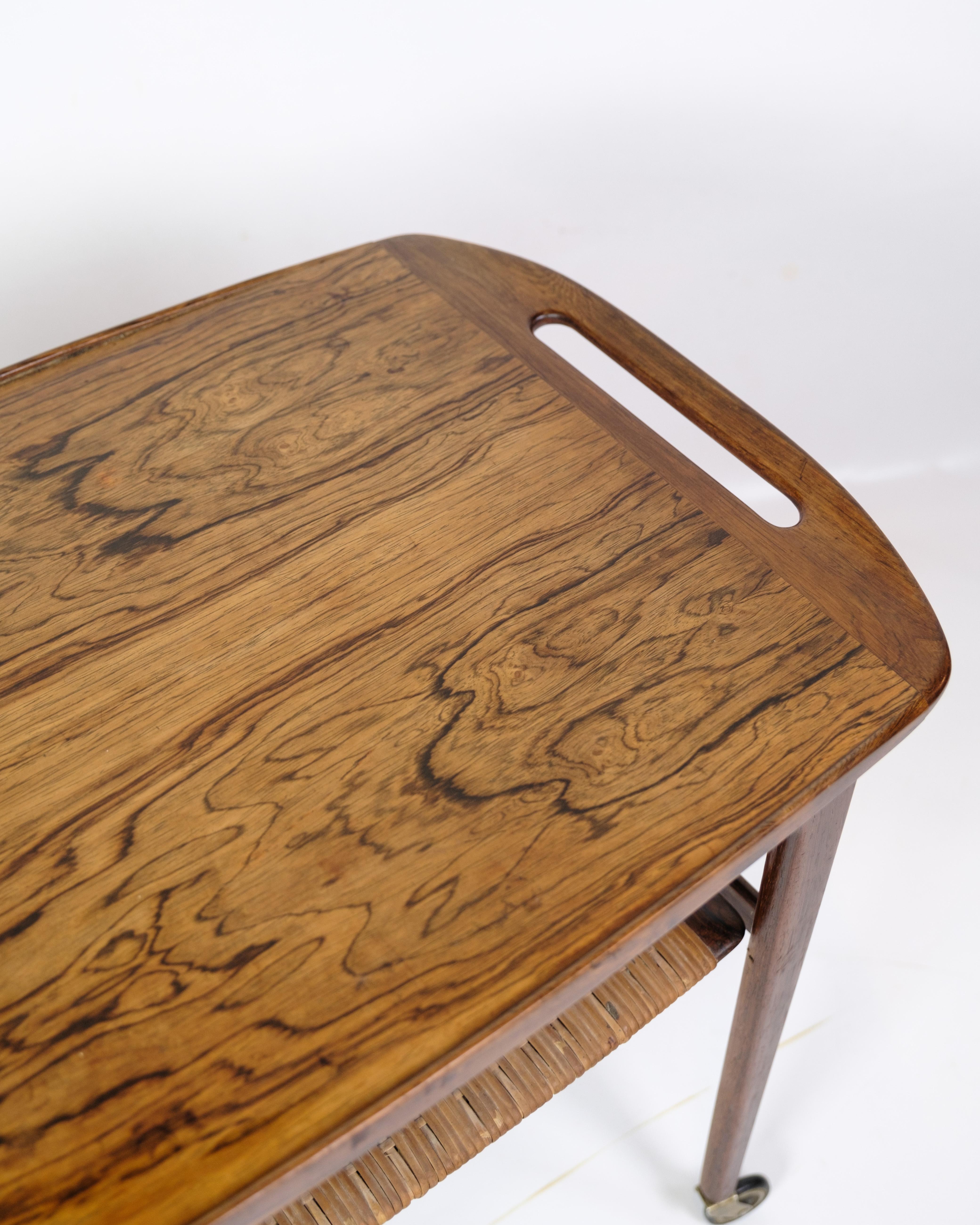 Rosewood serving trolley with wicker shelf, designed by Johannes Andersen and produced by CFC Silkeborg in the 1950s. The trolley combines the deep, warm hue of the rosewood with a light and functional wicker shelf, creating a unique contrast