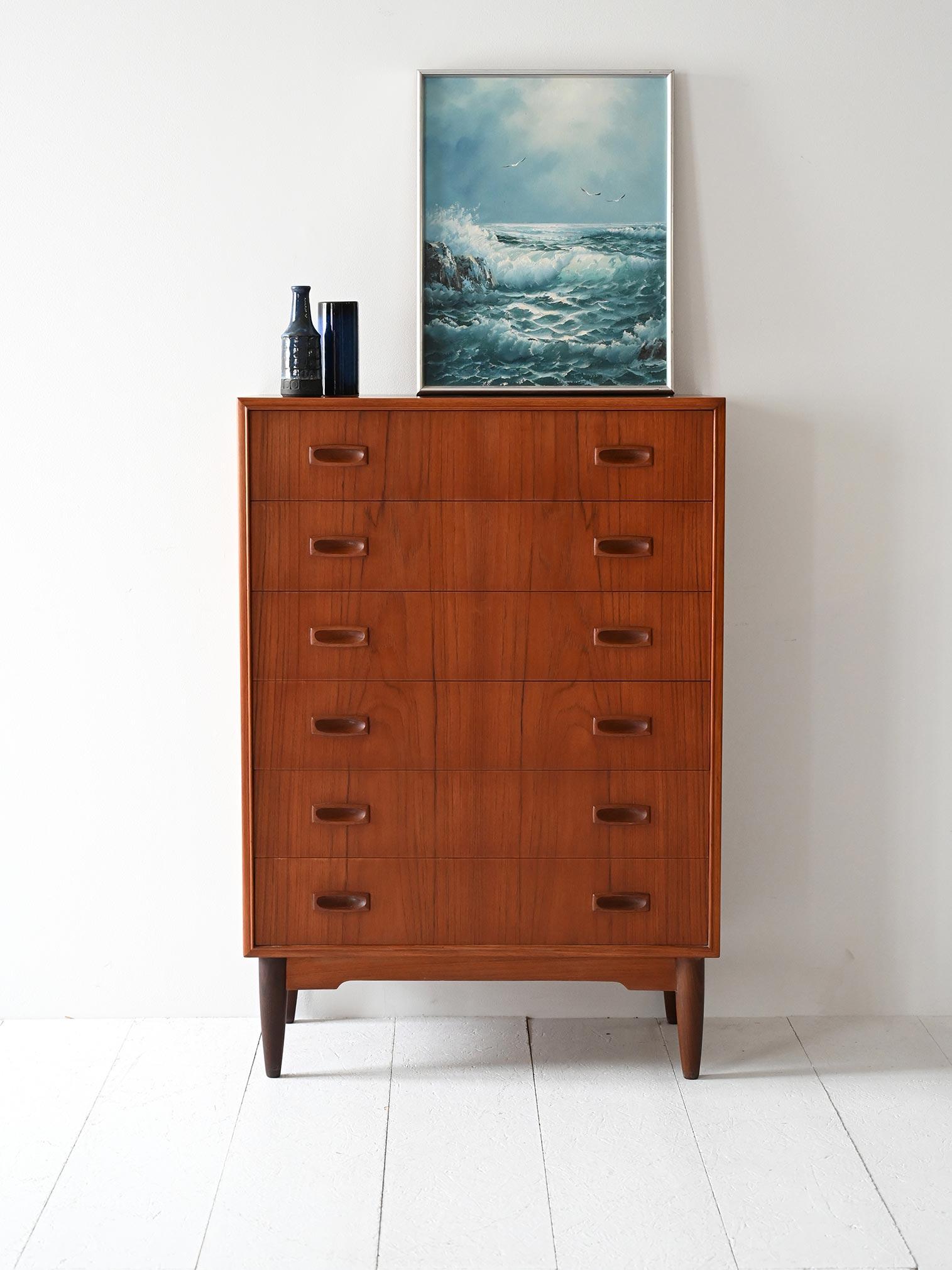 Sestina con sei cassetti, gambe affusolate e maniglie scolpite, in teak con venatura marcata e design equilibrato.

Profilo verticale e dettagli ben calibrati definiscono questa sestina scandinava degli anni ’60. I sei cassetti sono scanditi da