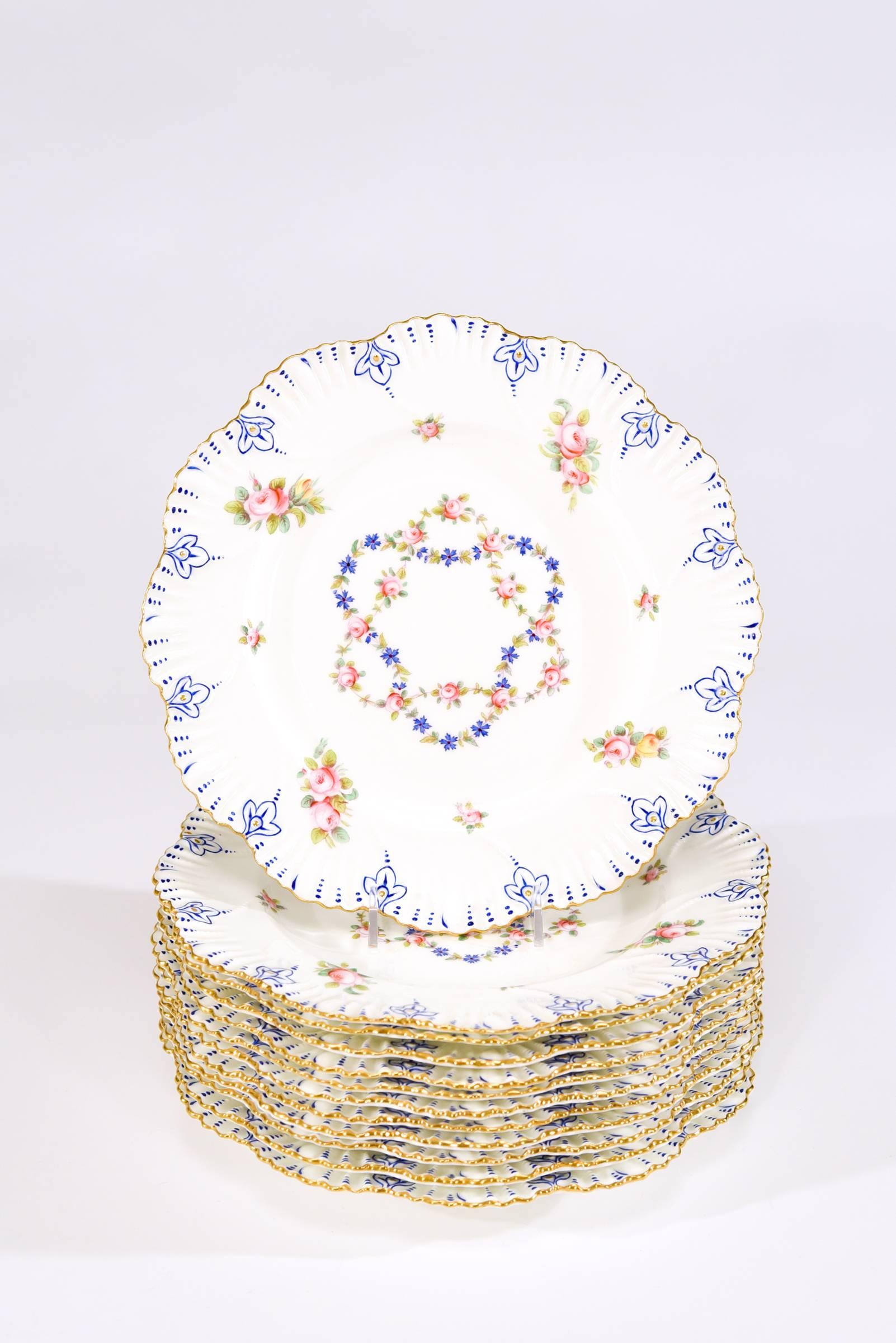 This set of 12 dinner plates were made by Coalport in 1889 and retailed by Gilman Collamore, New York. Evoking the colors and style of Sevres porcelain, they have shaped rims with molded relief and trimmed in gold. Hand-painted roses and