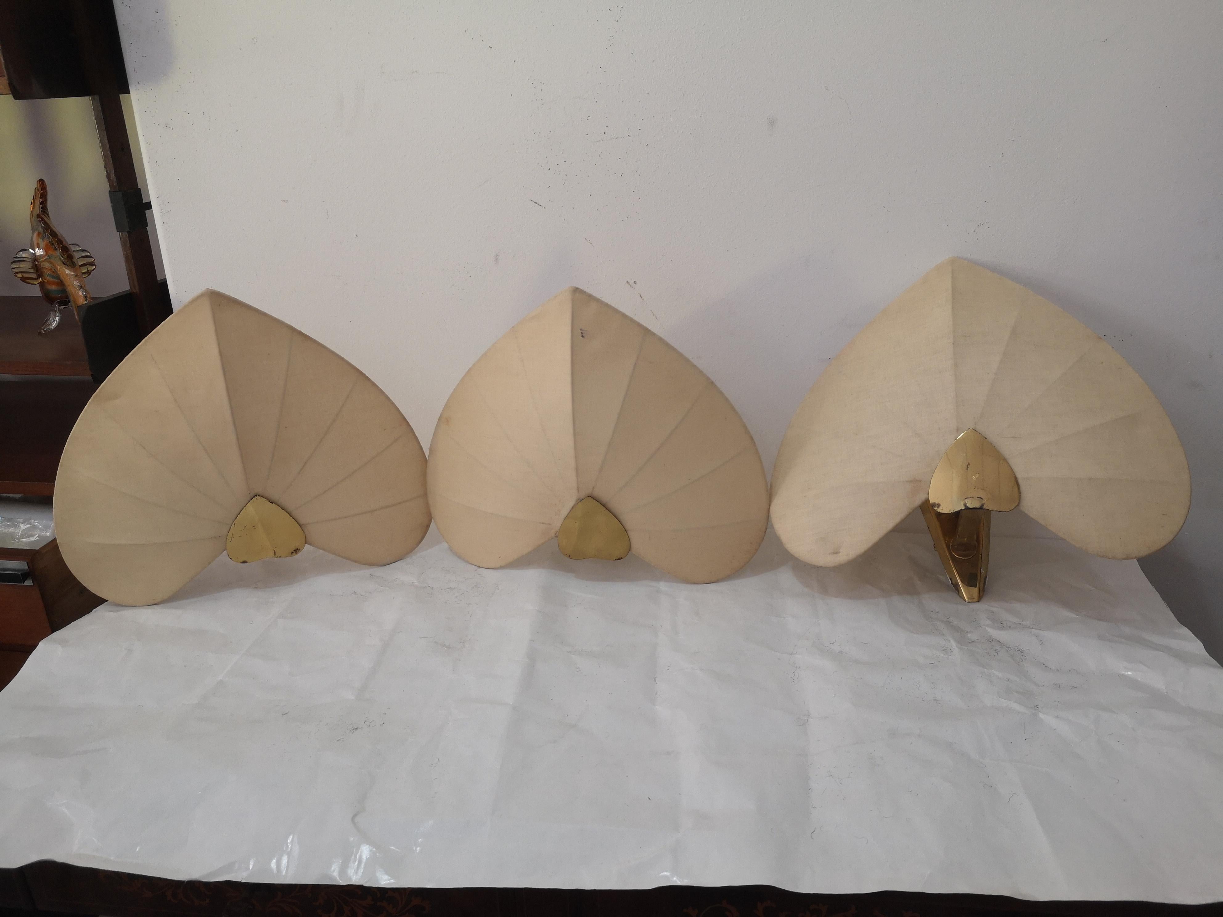 Set von 3 Paralumi in Forma di cuore, in tessuto, attribuite al designer Antonio Pavia negli anni '70 nello stile Hollywood Regency. 
Gli applique presentano tipicamente una struttura in ottone con steli e foglie a forma di cuore che nascondono le
