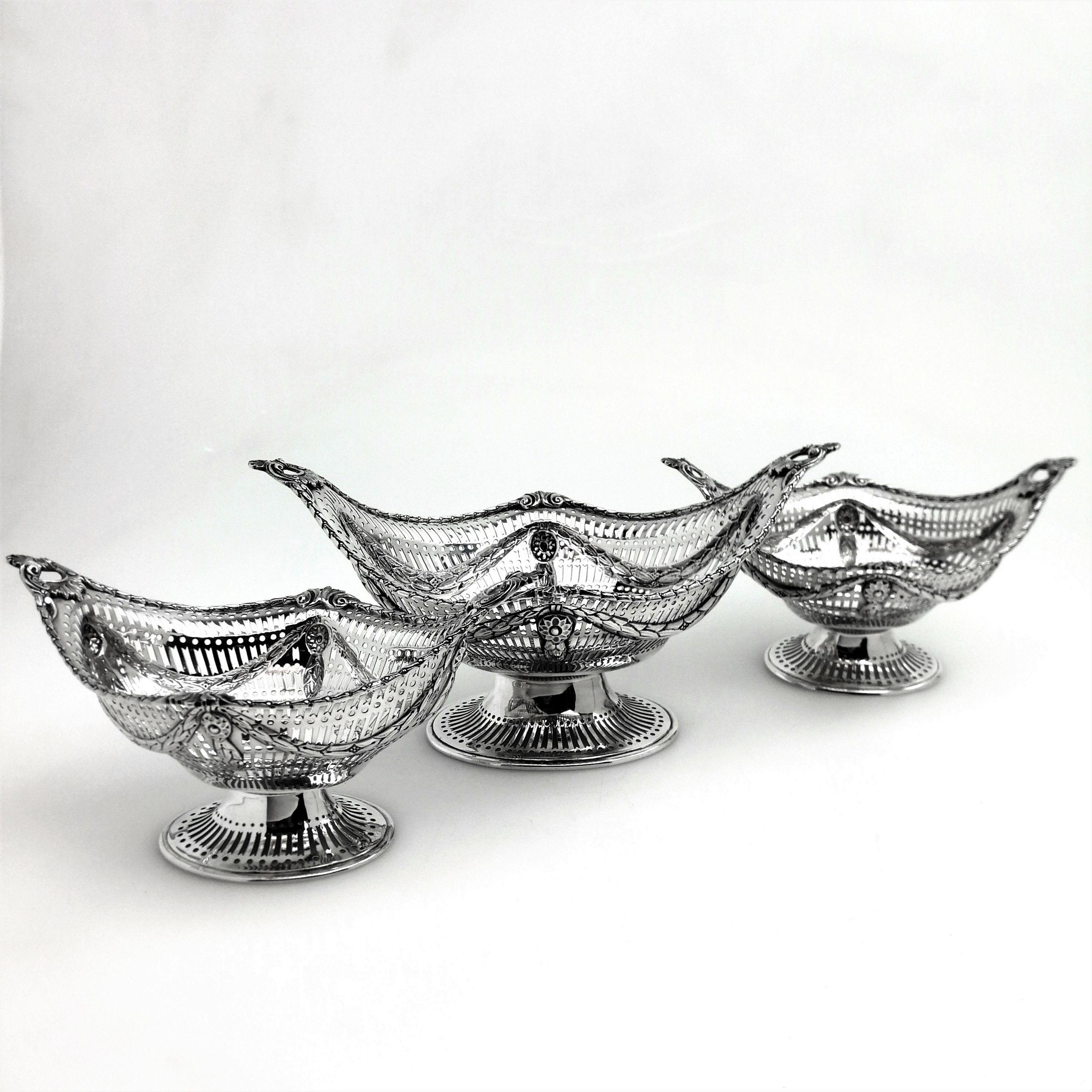 A set of 3 impressive Antique Victorian Silver Baskets - one of a larger size and the other two a matched pair. All three have the same traditional George III neoclassical Adams style with a shaped oval form standing on a pedestal foot. Each Basket