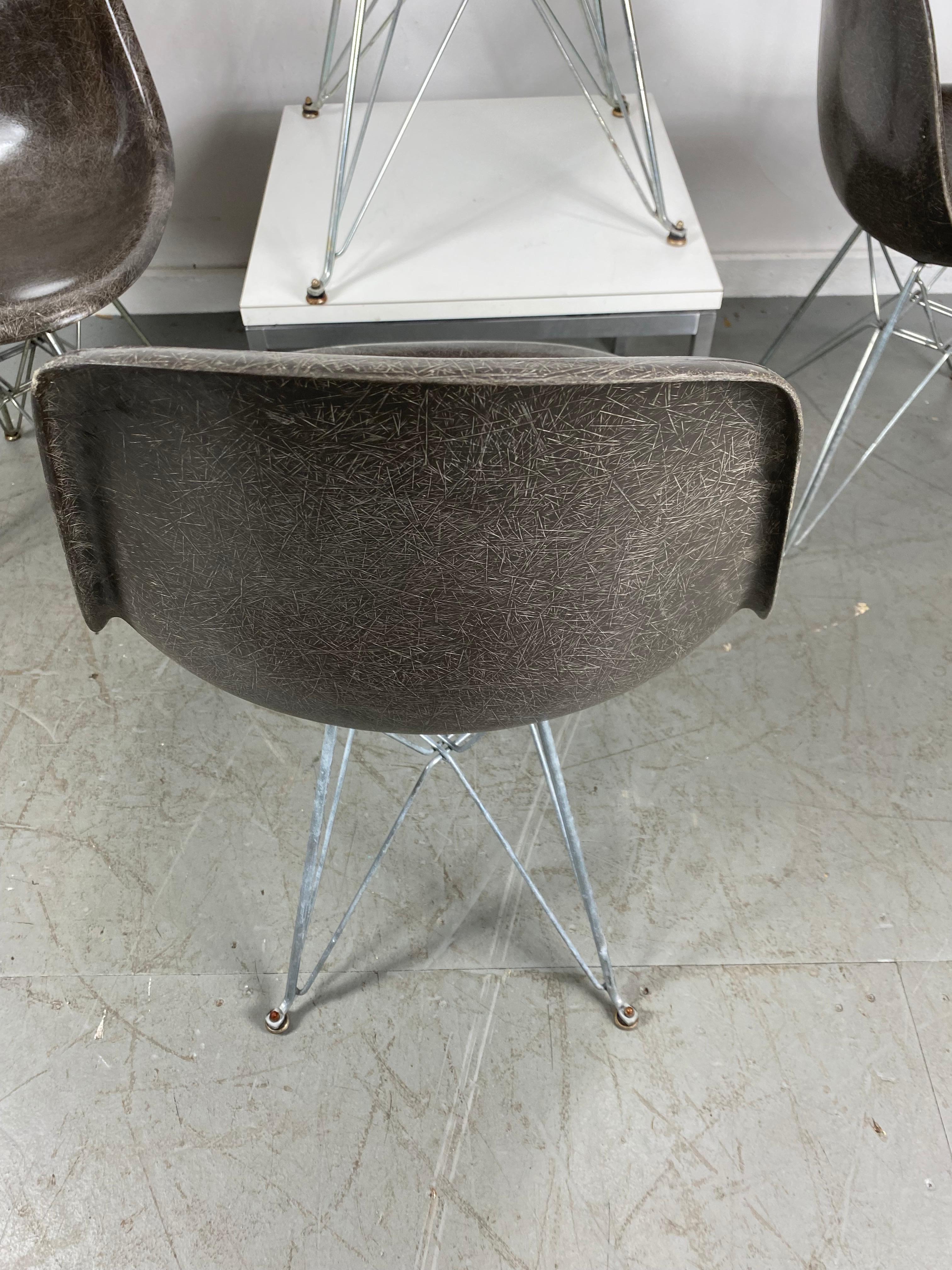 Nice early gray patina on a set of 4 Charles and Ray Eames fiberglass shell chairs. Wonderfull exposed fibers, earlier production with original slotted screws attaching Eiffel tower bases with original early foot (glides).