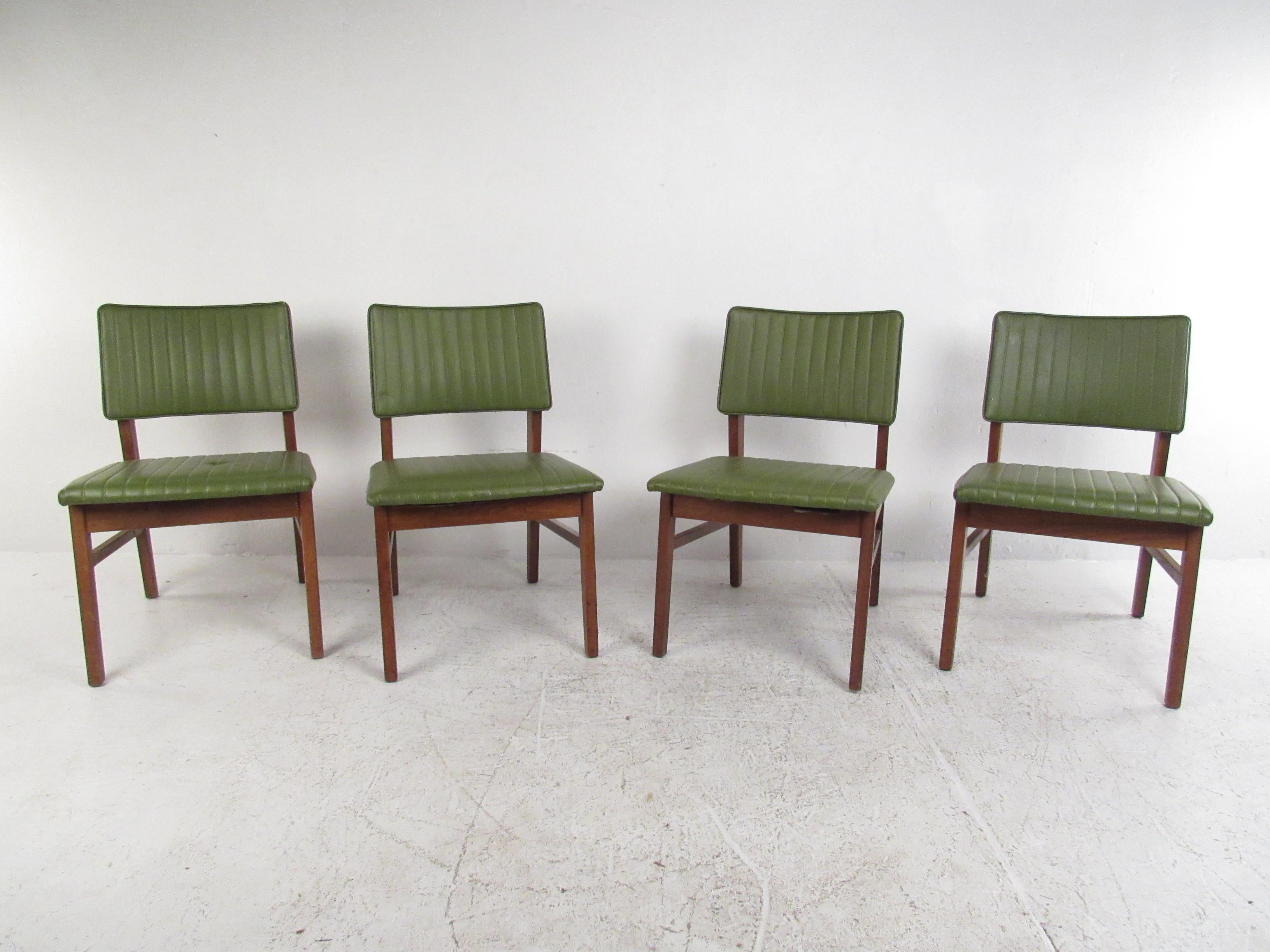 Stylish set of four Mid-Century Modern dining chairs made by the American manufacturer B.L. Marble Furniture Company. Angular solid wood frames with seats and backrests covered in a green faux-leather upholstery. Sure to be a great addition to any