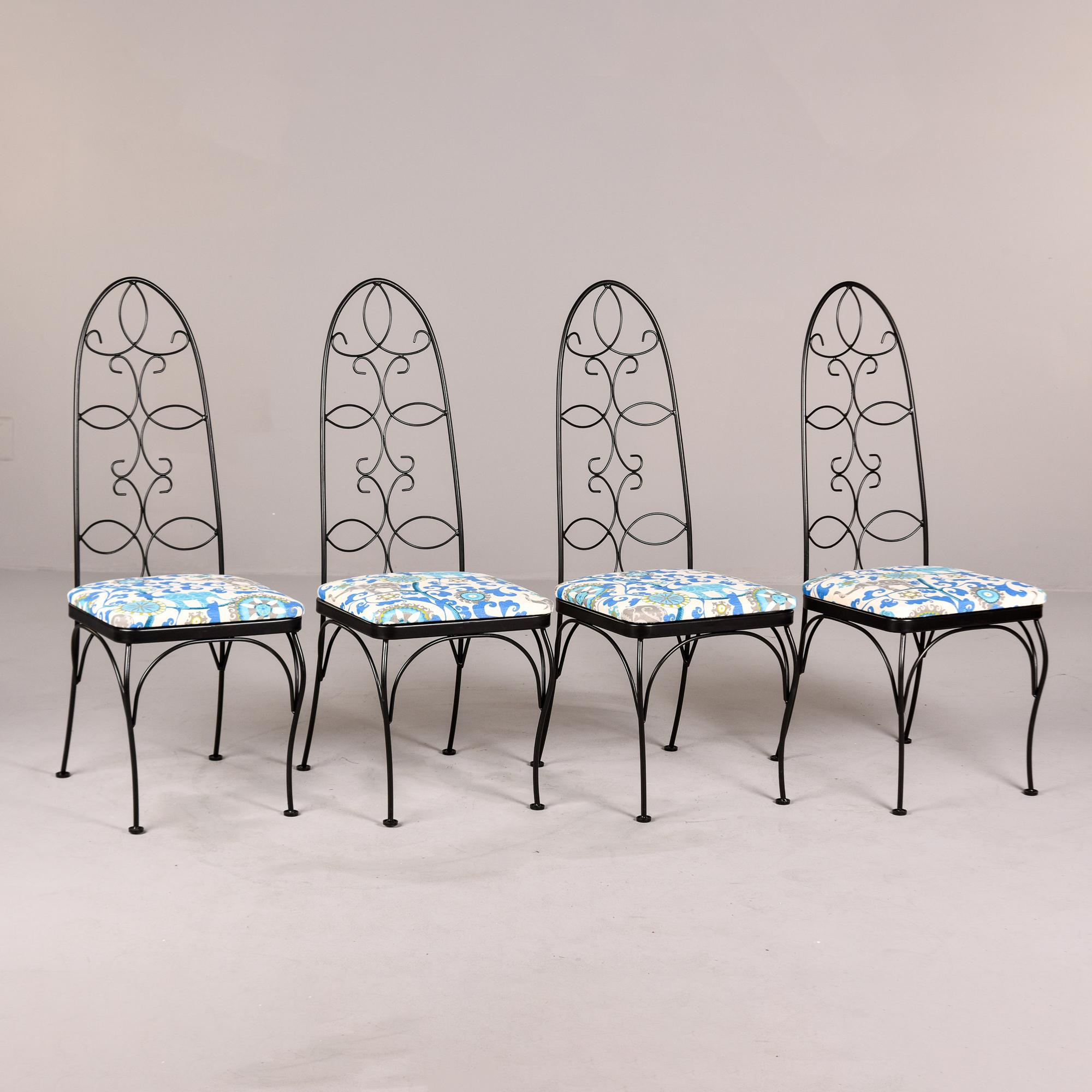 Set of four mid century patio chairs featuring scrolled wrought iron, high back frames painted in black. Newly upholstered seats in a fun, colorful outdoor fabric. Faint maker’s mark of Lloyd found on underside of one chair frame. We estimate these