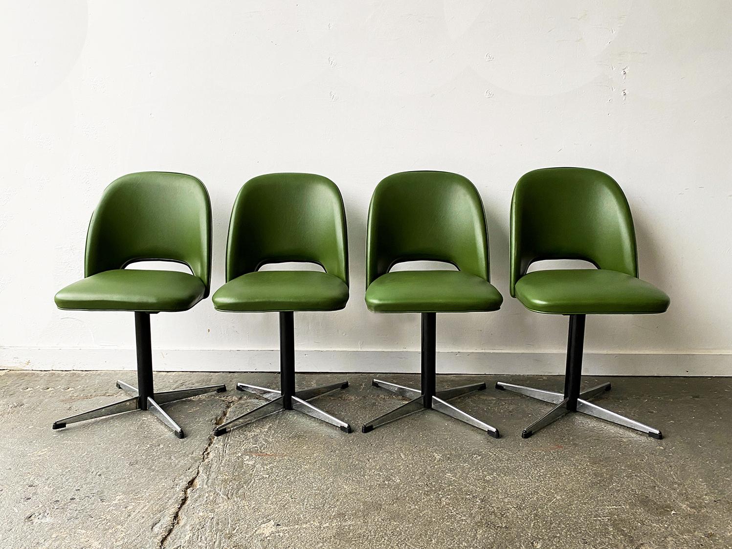 A set of four single stem swivel chairs, with the original green vinyl upholstery. Standing on four prong steel splayed feet with all rubber tips intact. 

Size 
Width 44cm x depth 51cm x height 83cm x seat height 46cm

Material
Vinyl / leatherette.