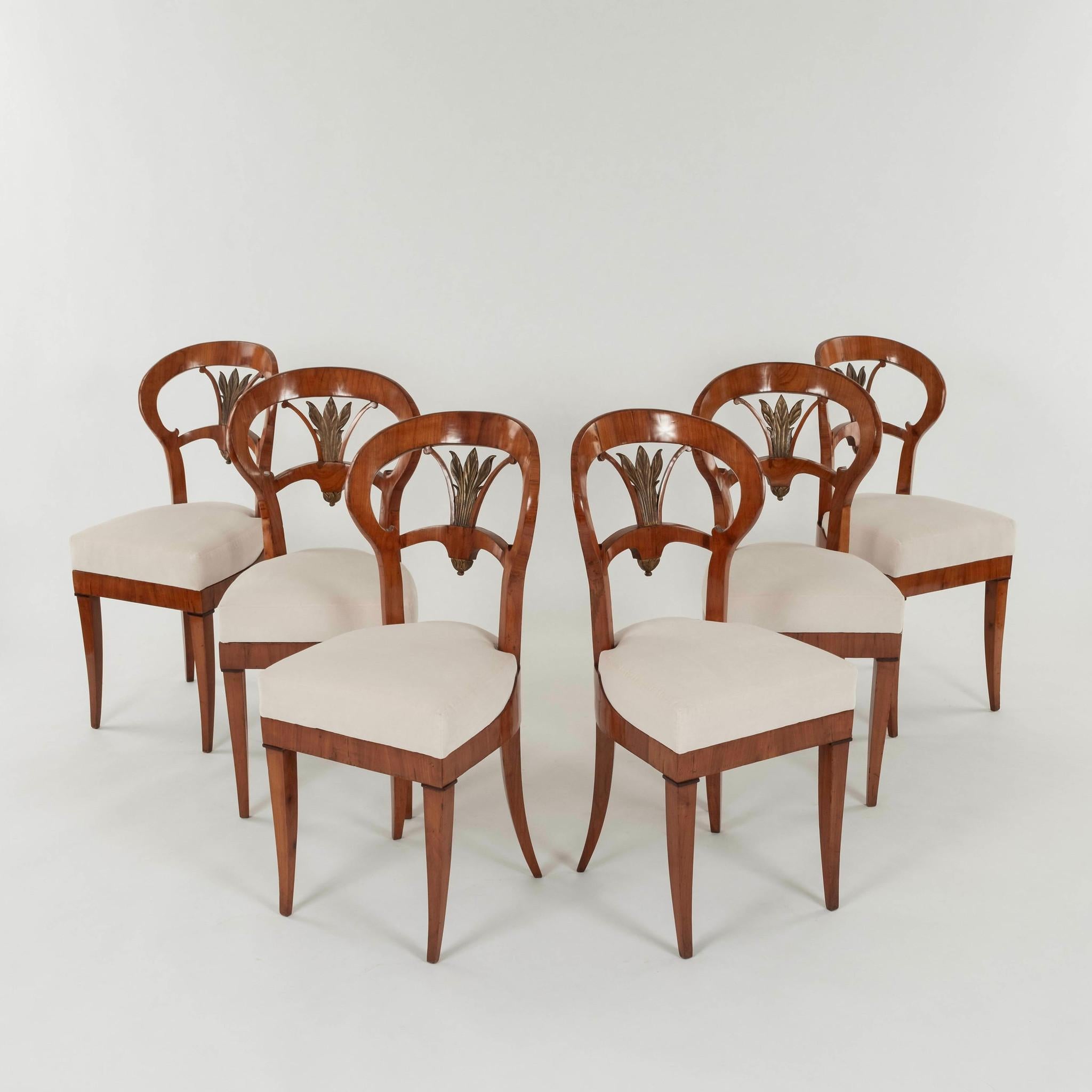 Satz sechs  Biedermeier Esszimmerstühle. Diese hübschen Stühle  weisen handgeschnitzte Details, gemischte Hölzer, Vergoldung und neu gepolsterte Sitze auf.