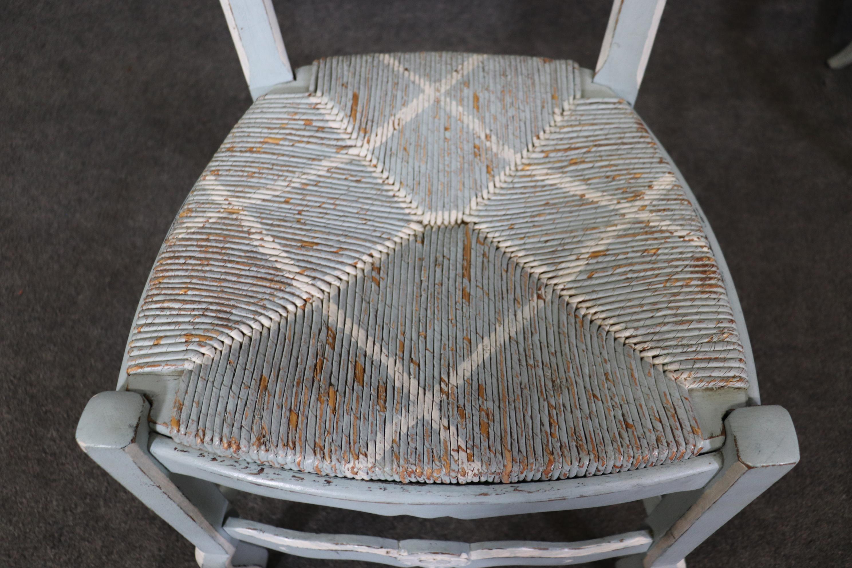 This is a gorgeous set of rush seated country chairs made in France and they are painted in a distressed blue and white finish with a cross hatched design on the seats. They are in good vintage condition with signs of distressing and signs of use