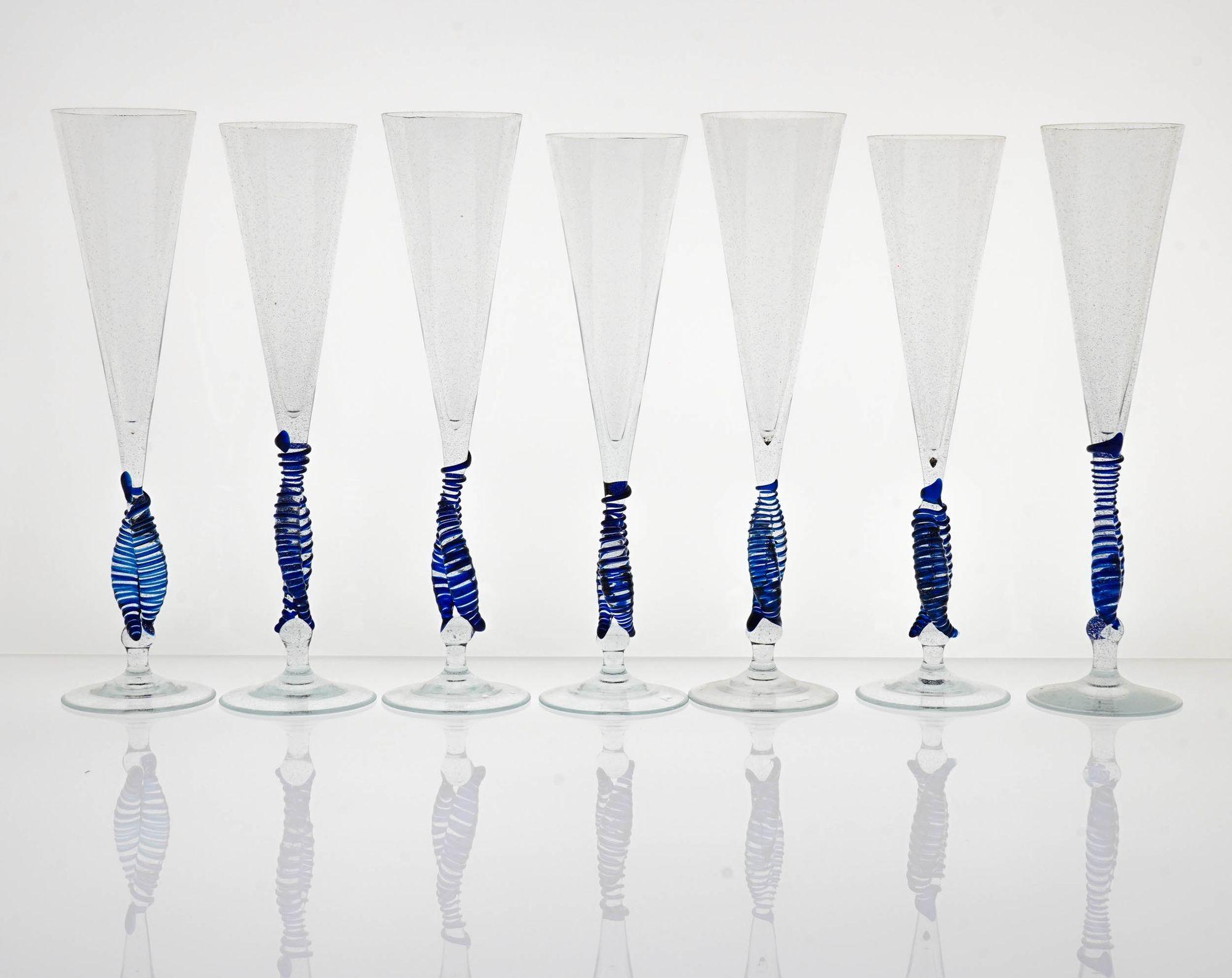 Questo set unico di flauti del Cenedese è un reperto raro ed esclusivo. Realizzati a Murano negli anni '50 da uno dei migliori vetrai dell'epoca, questi flauti sono completamente fatti a mano e presentano una delicata perla a spirale blu cobalto sul