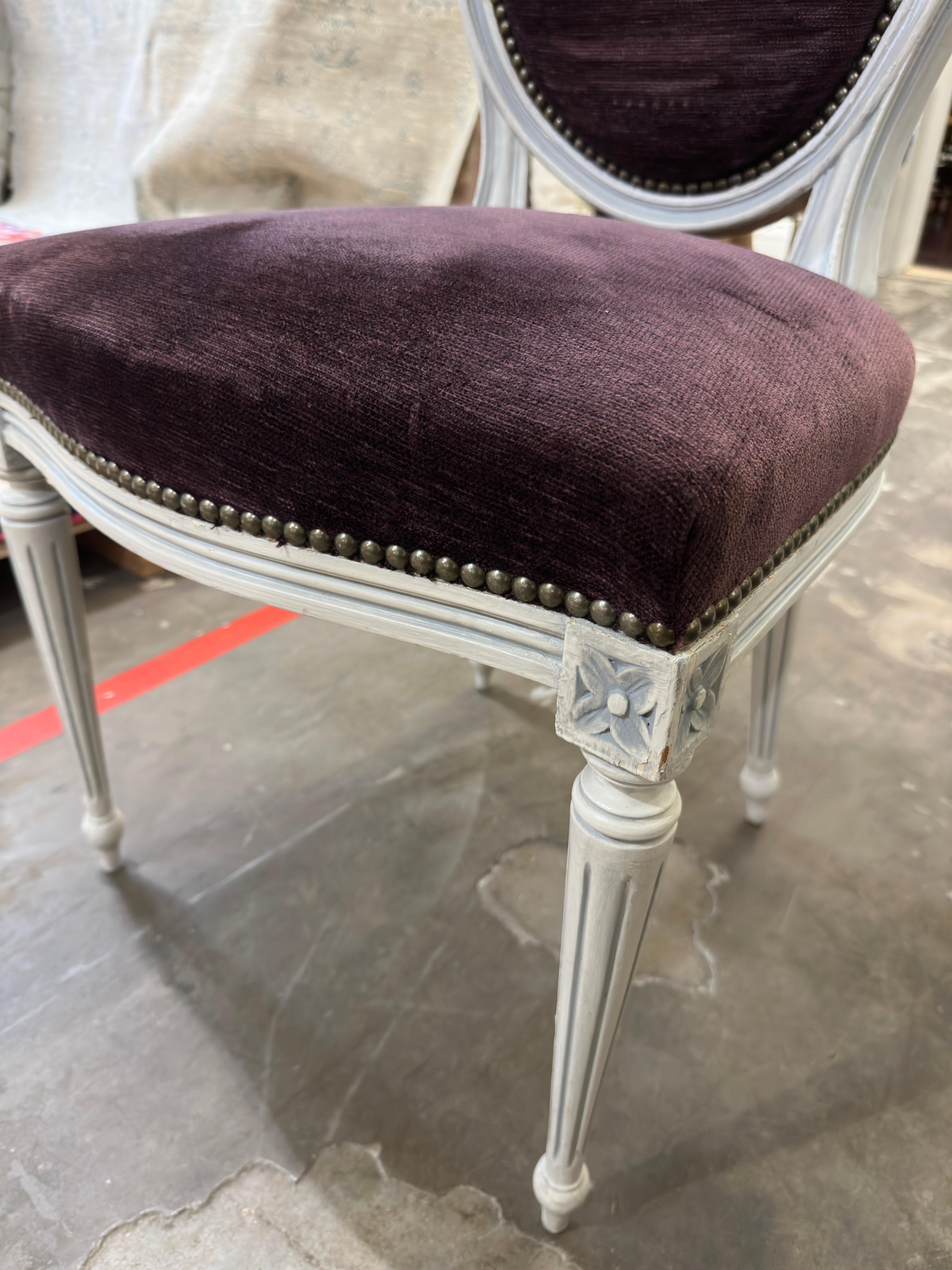 This is a set of eight (8) French dining chairs is in the Louis XV style. Each chair is beautifully upholstered in a rich and dark purple currant velvet with the wood in a whitewashed finish. Each chair is very sturdy, no visible damage and the