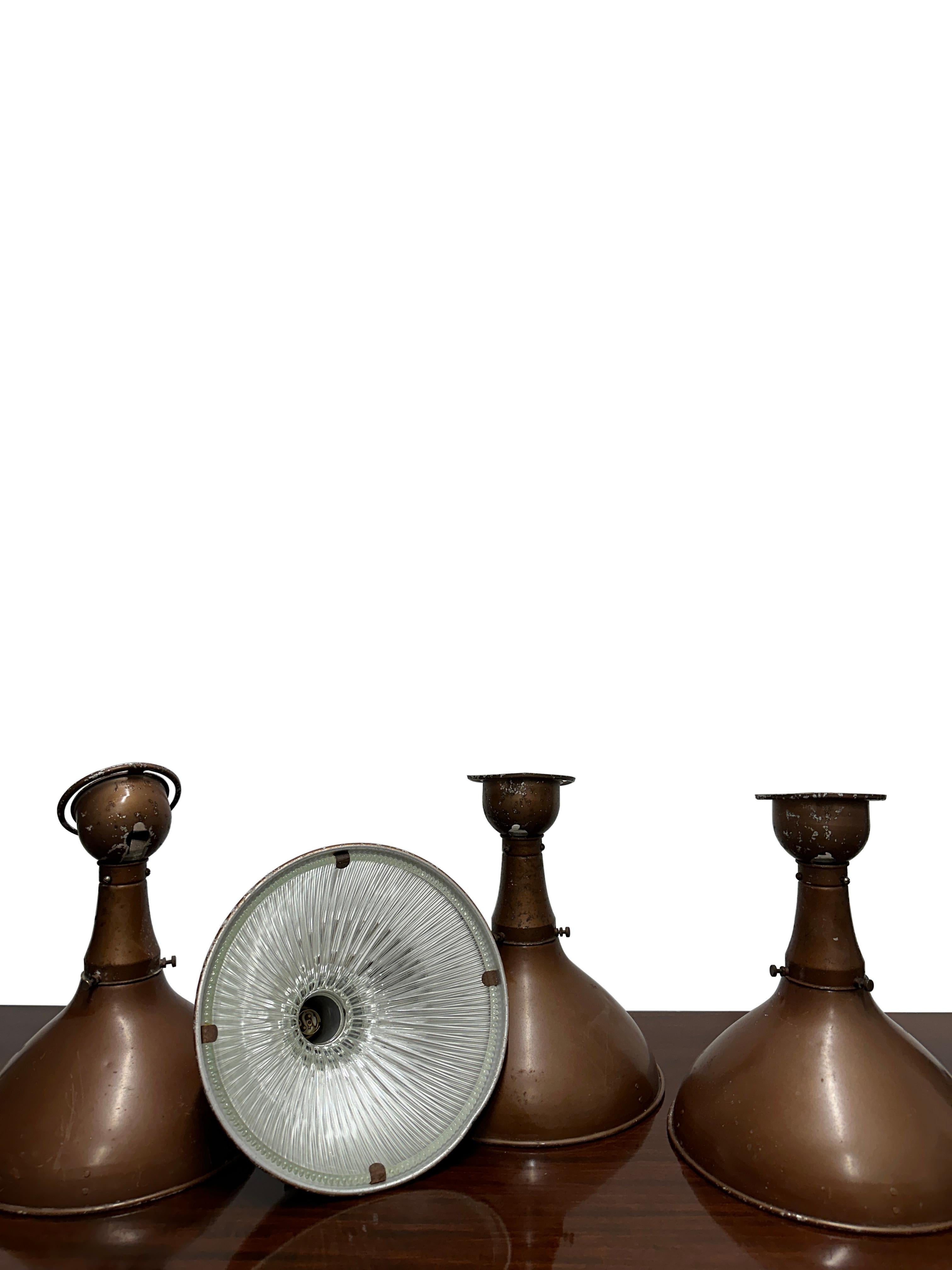 - An early set of four industrial wall lights by Holophane in their original bronze finish, England circa 1920.
- The lights are adjustable in all directions and retain their original fully stamped Holophane glass inserts.   The wall plate features