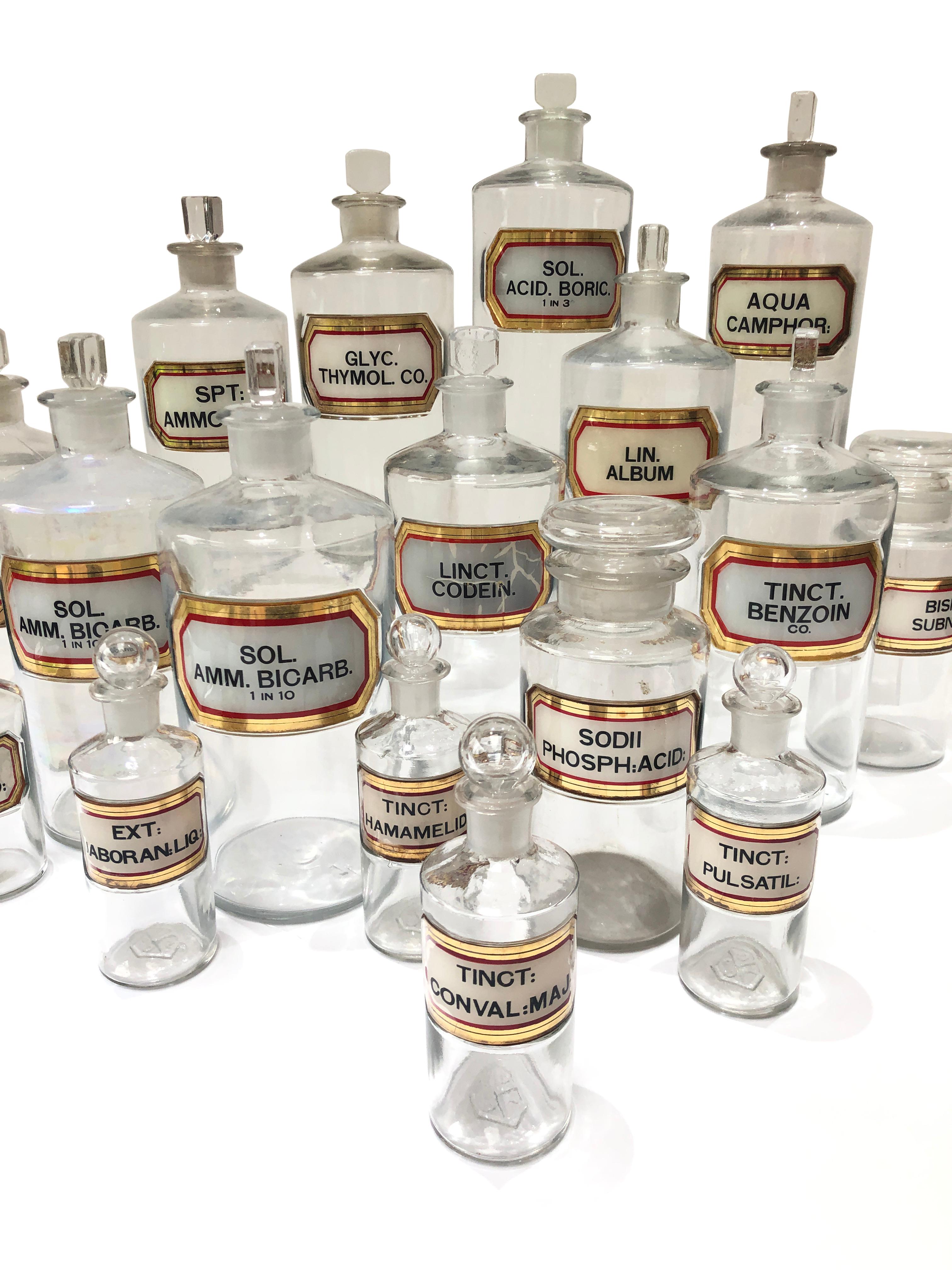 - A fabulous collection of 18 clear glass Victorian apothecary bottles, circa 1900. 
- All have excellent glass and gilt lettered and painted plaques to the front, with original glass stoppers. 
- Mixed sizes, shapes and conditions. The size