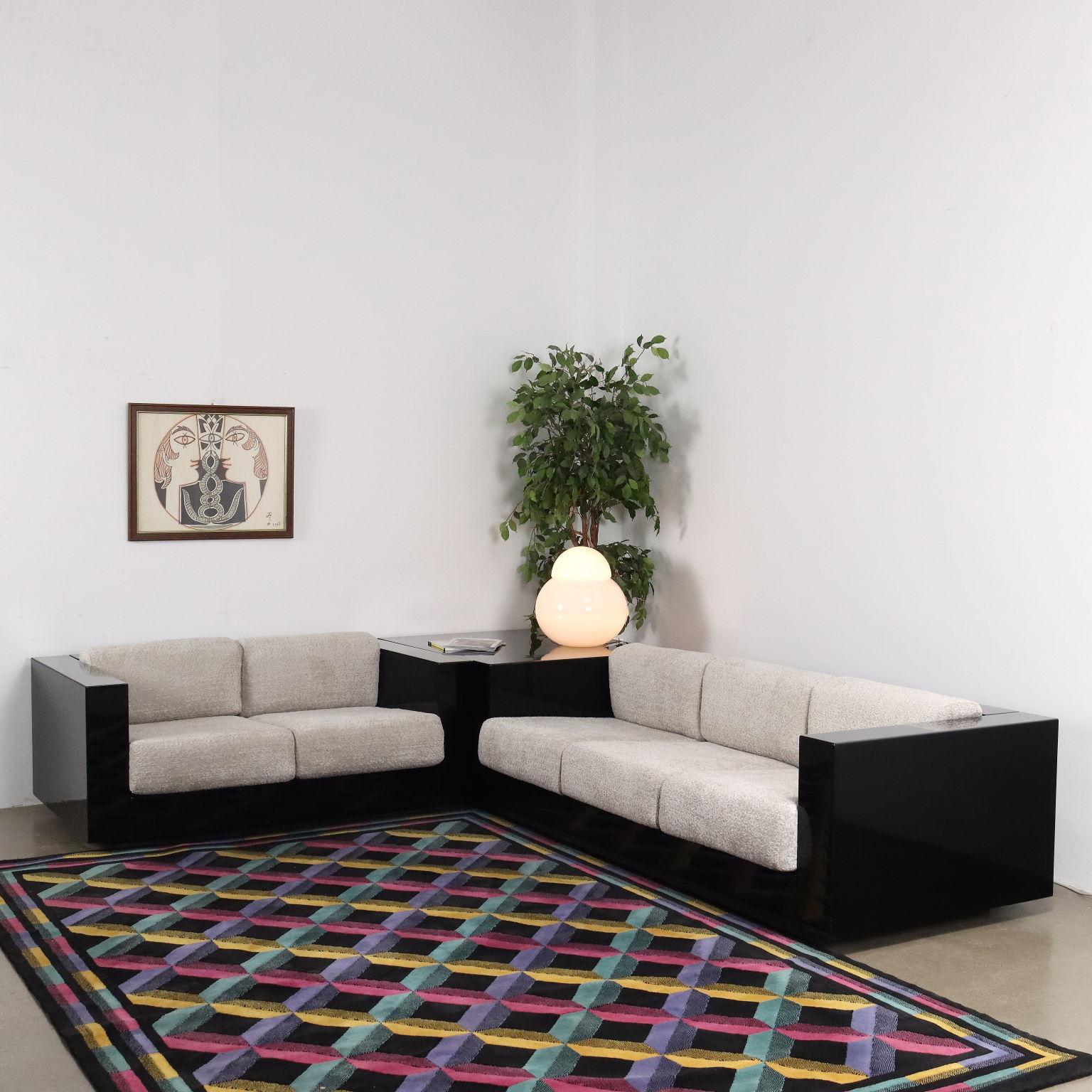 Pareja de sofás, uno de dos plazas y otro de tres plazas, modelo 'Saratoga' con estructura de madera lacada en negro, cojines recién retapizados con relleno de espuma y funda de tela en tonos grises. Una mesita, también de madera lacada en negro, a