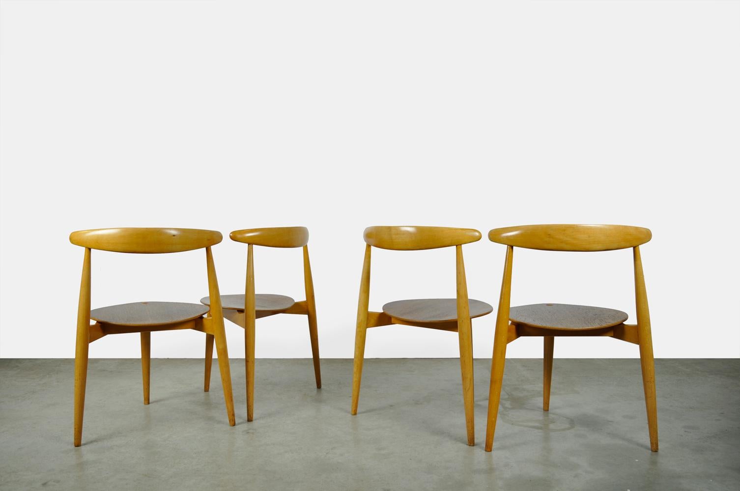 Beautiful set of 4 dining table chairs, designed by Hans J. Wegner and produced by Fritz Hansen, Denmark 1950s. The triangular construction of the special chairs is a combination of beech and teak wood. The frame is made of birch and the plywood