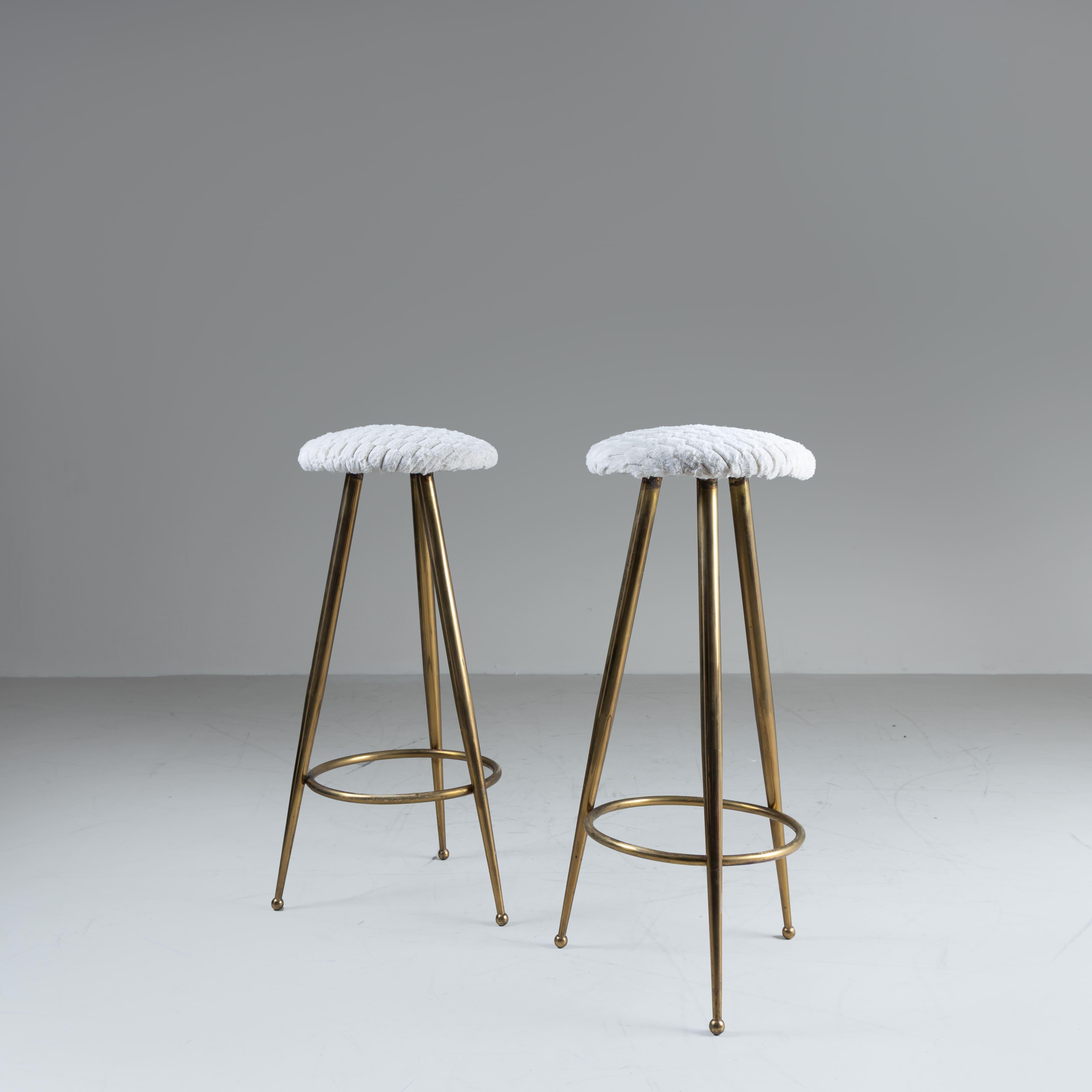 Set di 2 sgabelli, Italia, 1970. Struttura in ottone lucidato dal design elegante e minimale, abbinata a una raffinata tappezzeria in velluto bianco con motivi geometrici. Il contrasto tra la lucentezza dell’ottone e la texture morbida del velluto