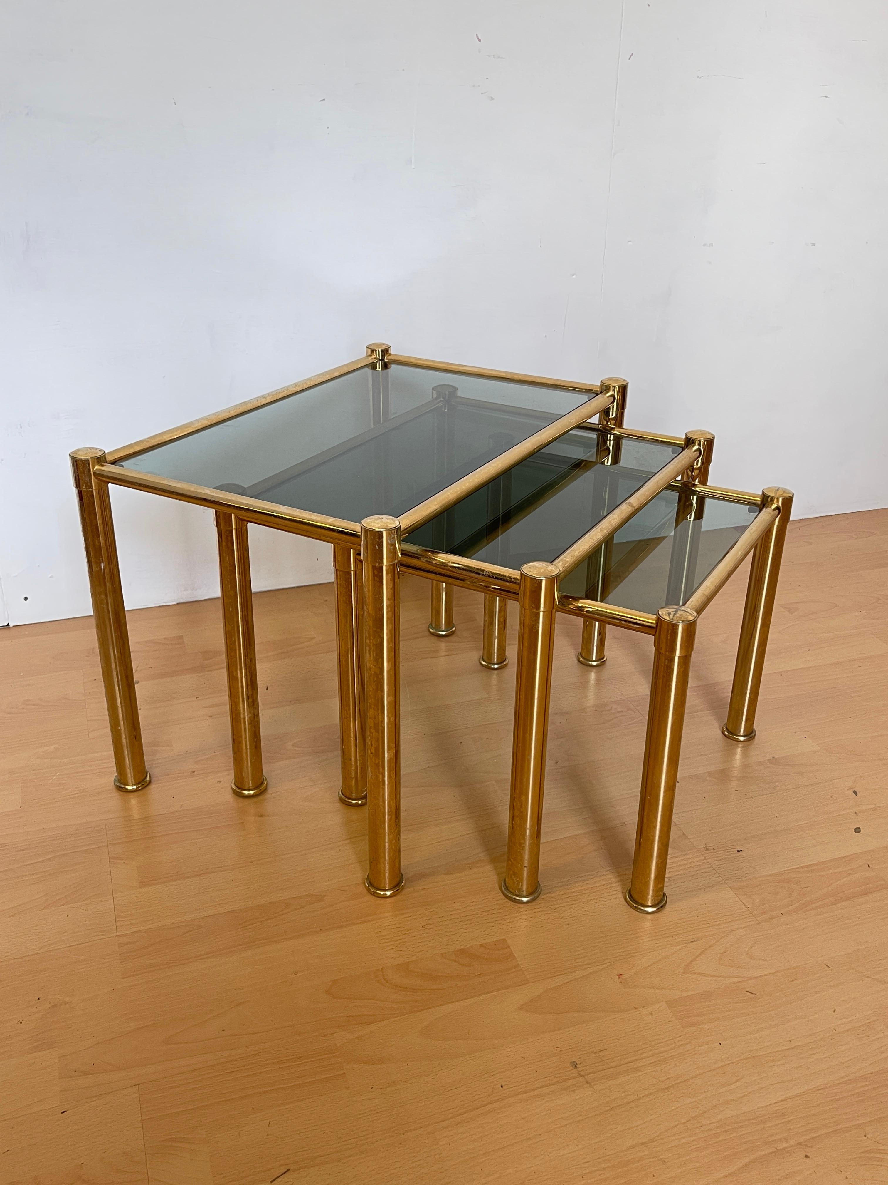 Elegante set di tavolini da salotto in ottone lucido e vetro trasparente aggiunge un tocco di modernità e lusso a qualsiasi ambiente. Con una struttura raffinata in ottone dorato e ripiani in vetro, questi tavolini sono perfetti per chi cerca mobili