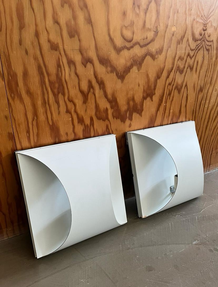 Set of 4 geometric enameled metal wall sconces, Italian production - 1970s
Series of four anonymous wall sconces with an essential design, made of white enameled metal. The shapes are achieved through skillful bending of sheet metal, in perfect