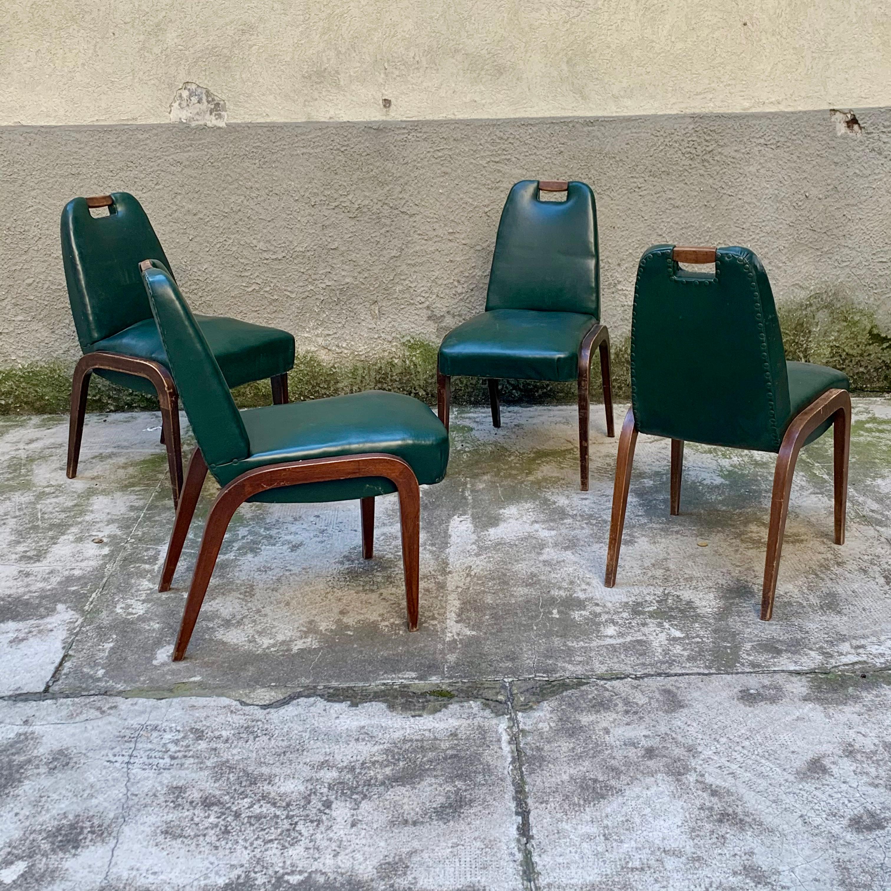 Ces chaises sont caractérisées par une poignée en bois sur le dossier et des pieds sur le côté. Elles sont recouvertes d'un cuir vinyle vert, toujours d'origine.
