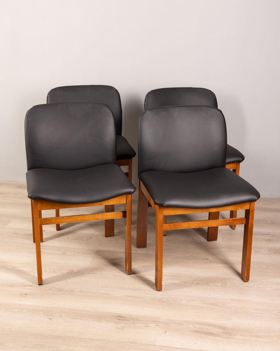 Set of four chairs with wooden frame and seat and back covered in black leather, Italian design, 1970s.

CONDITION:
In good, working condition, may show signs of wear given by time.

SIZING: 
Height 78 cm; Width 50 cm; Length 50 cm

MATERIALS: 
Wood