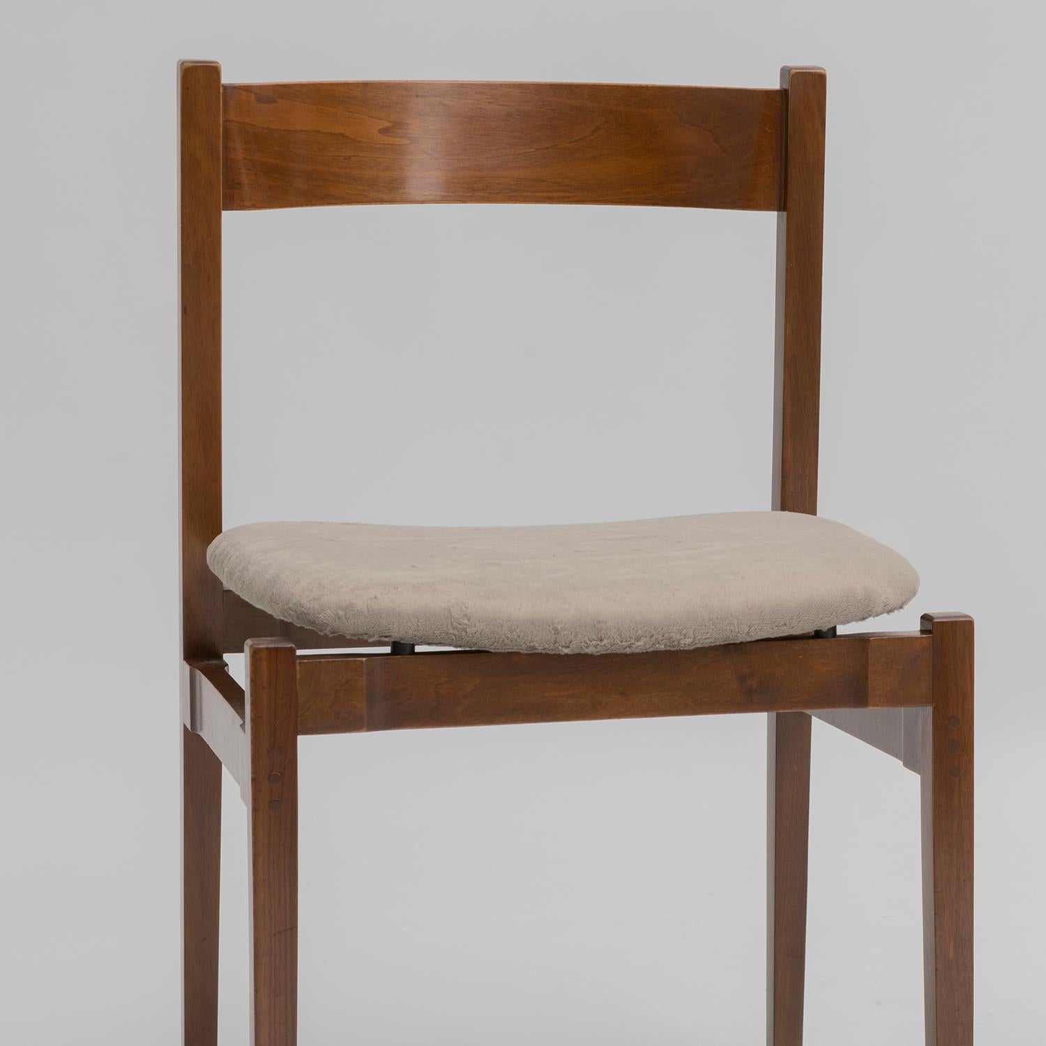 Set di sei sedie in noce modello 1001, disegnate nel 1960 da Gianfranco Frattini e prodotte da Cassina. Recano le etichette originali, le sedute sono state restaurate usando un bel simil velluto  a pelo medio, grigio. La parte legno è stata