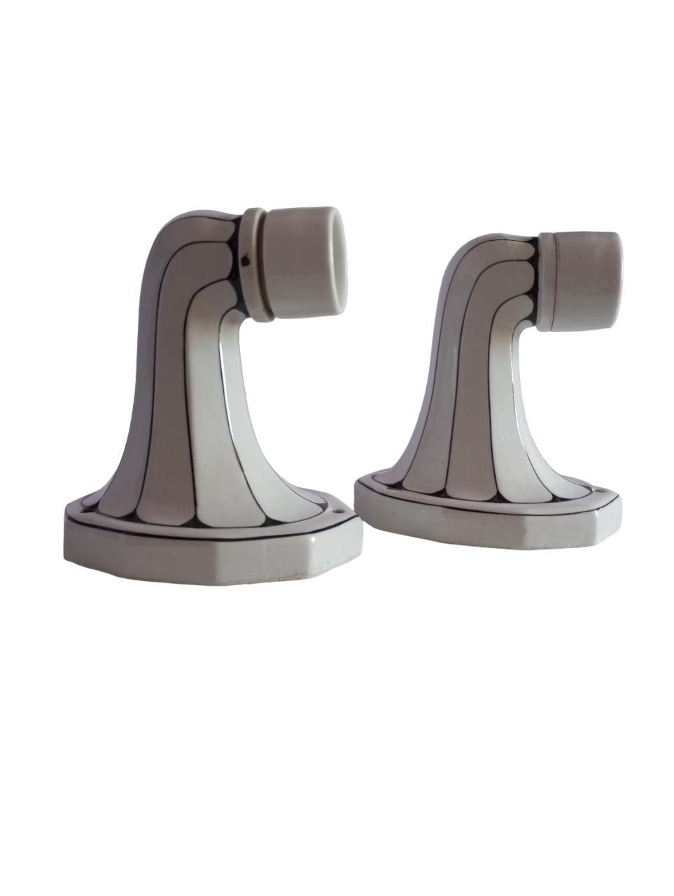 Queste appliques da parete, realizzate negli anni ’60, sono un raffinato esempio di stile Art Nouveau. Il braccio in porcellana smaltata, caratterizzato da un’elegante combinazione di bianco e nero, esprime armonia cromatica e fluidità delle linee,