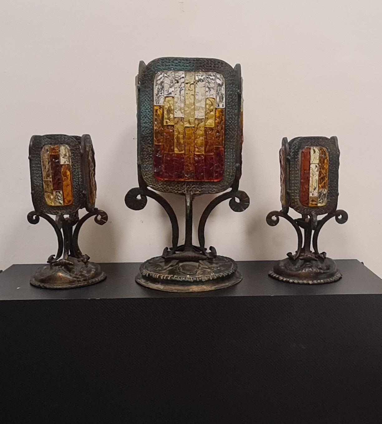 Set consisting of 3 table lamps in Brutalist style attributable to Poliarte.

3 particular lamps including a large central one and two smaller side abat-jours.

Made in the 1970s from hand-wrought iron and murano glass mosaics in shades of