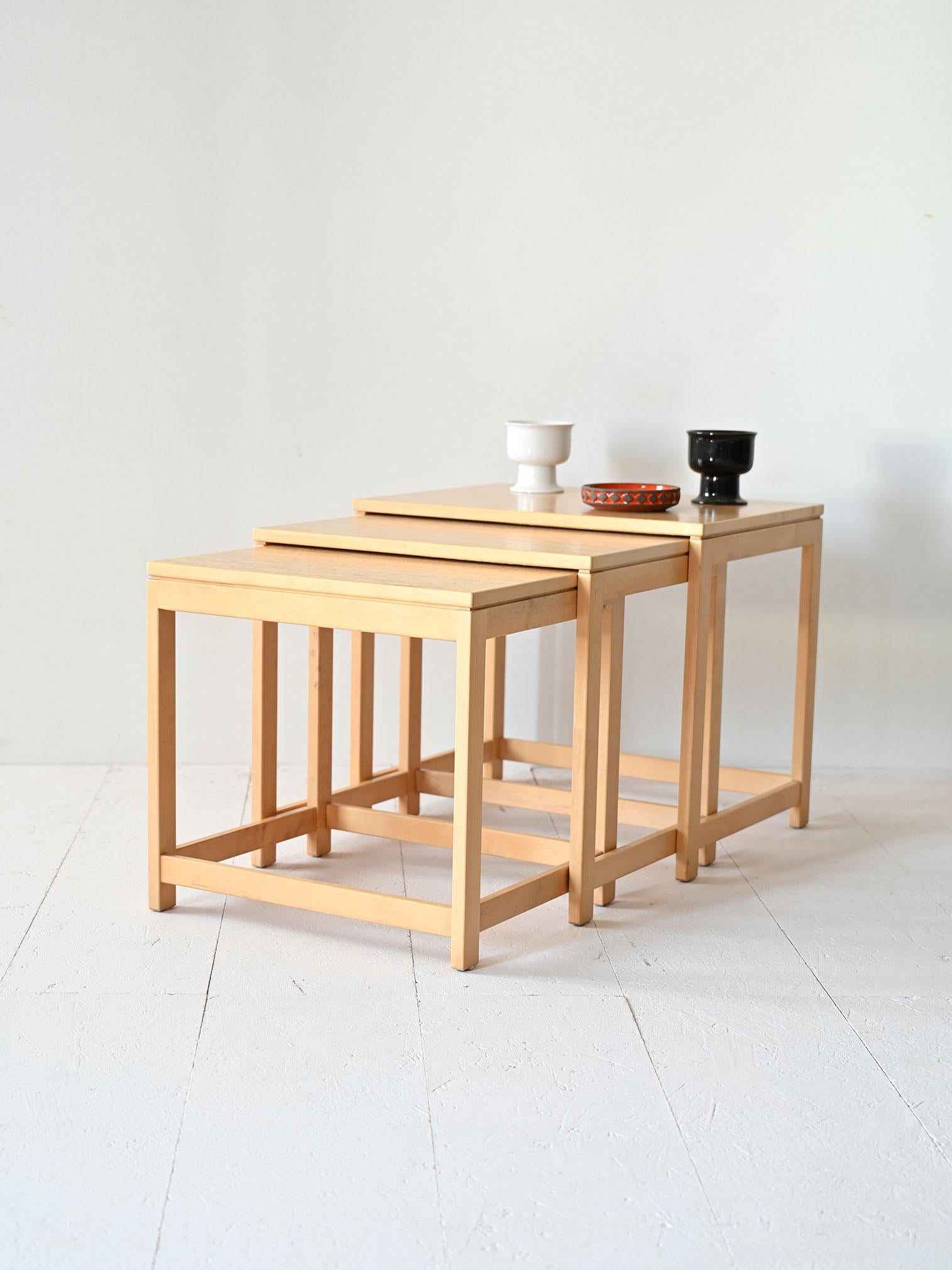 A set of three light wood nesting tables featuring square, essential and modern lines. The nesting design allows the tables to be stored one under the other when not in use, optimizing space and offering versatility.

Each side table in the set