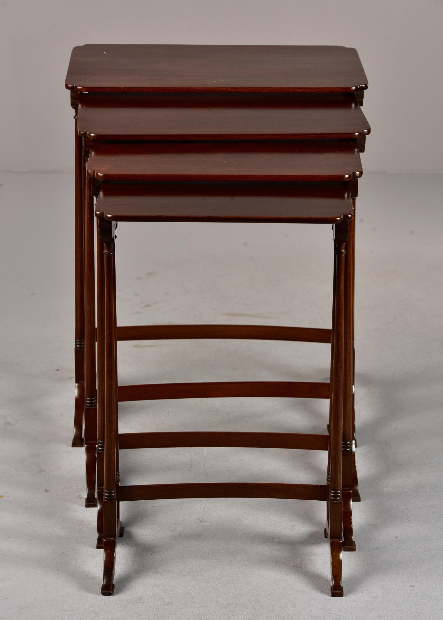 Circa 1920s set of four English mahogany nesting tables with slender frames and bases. Unknown maker. 

#1 = 28” h x 22” w x 16.25” d (top surface: 22” w x 14.75” d)
#2 = 27” h x 20” w x 14.5” d (top surface: 20” w x 13.5” d) 
#3 = 26” h x 18” w