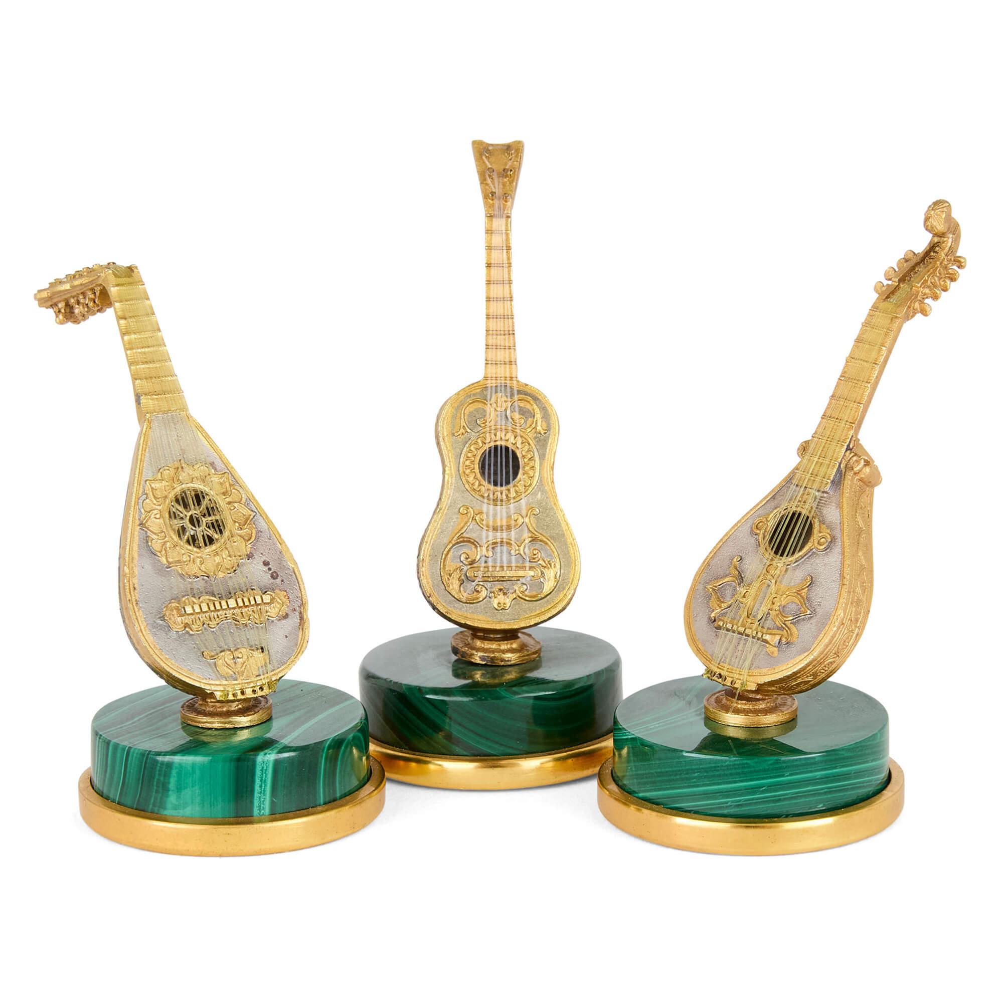 Set di otto figure di strumenti musicali italiani in miniatura in argento dorato e malachite 
Italiano, XX secolo 
Il più grande (chitarra): Altezza 6,5 cm, diametro 3,3 cm

Un delizioso esempio di artigianato italiano, questo set in miniatura di