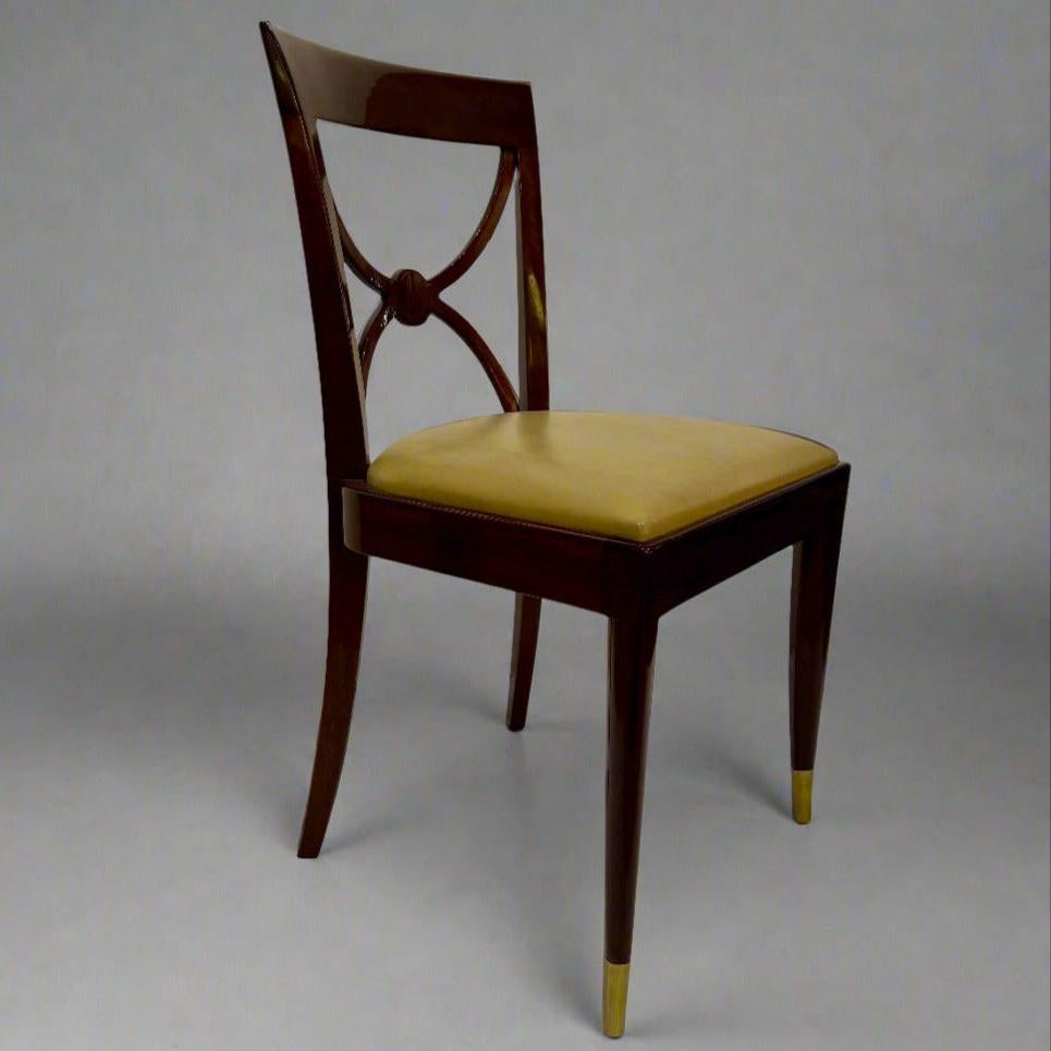 A set of four De Coene Frères designed Art Deco period side chairs from France circa 1930. Each chair is constructed of mahogany with patinated bronze sabots. The elegant double demilune in each back is joined by a circular disc.