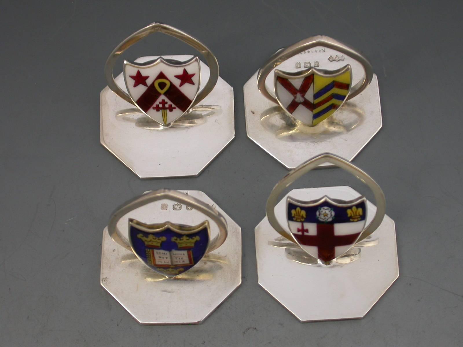A composed set of four or two pairs of early 20th century silver and enamel Oxford University menu holders, the shield shaped stands on octagonal bases enameled with the Coats of Arms of Oxford University and Merton College, plus two