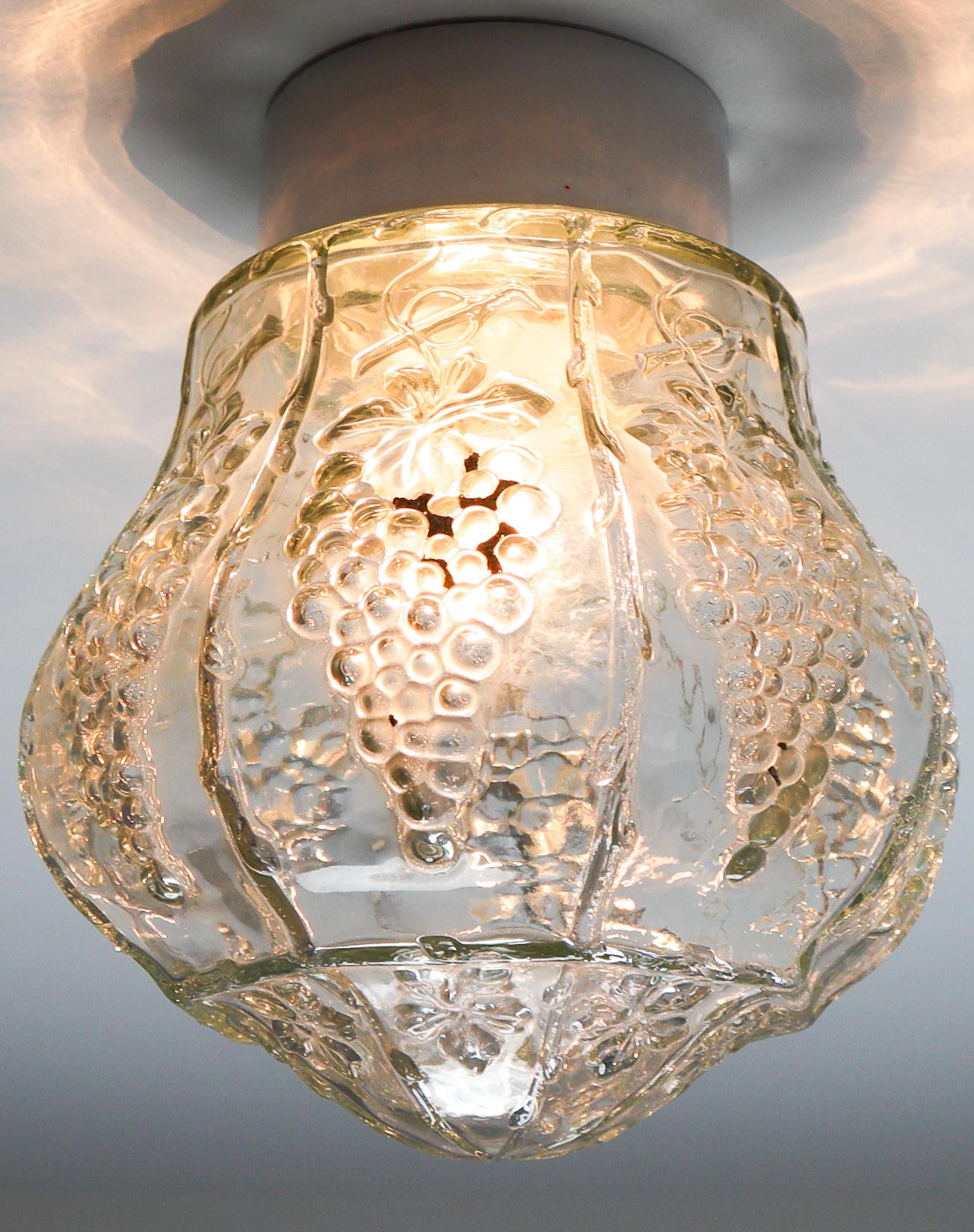 Set of two vintage modern wall/ceiling lights with clear structured glass and porcelain base, France 1930s. The glass has pattern in it, what gives a nice diffuse light effect and a nice pattern on ceiling and walls, these wall scones/ceiling lights
