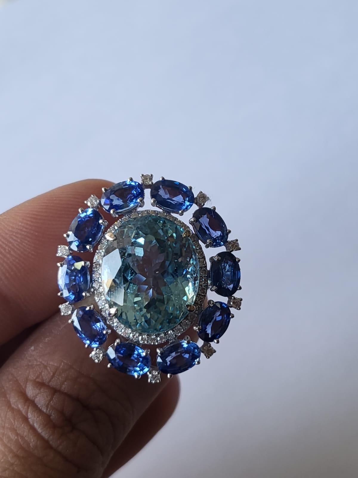 A very gorgeous and one of a kind, Aquamarine & Blue Sapphire Cocktail / Engagement Ring set in 18K White Gold & Diamonds. The weight of the round Aquamarine is 12.00 carats. The weight of the Blue Sapphire ovals is 5.95 carats. The Blue Sapphires